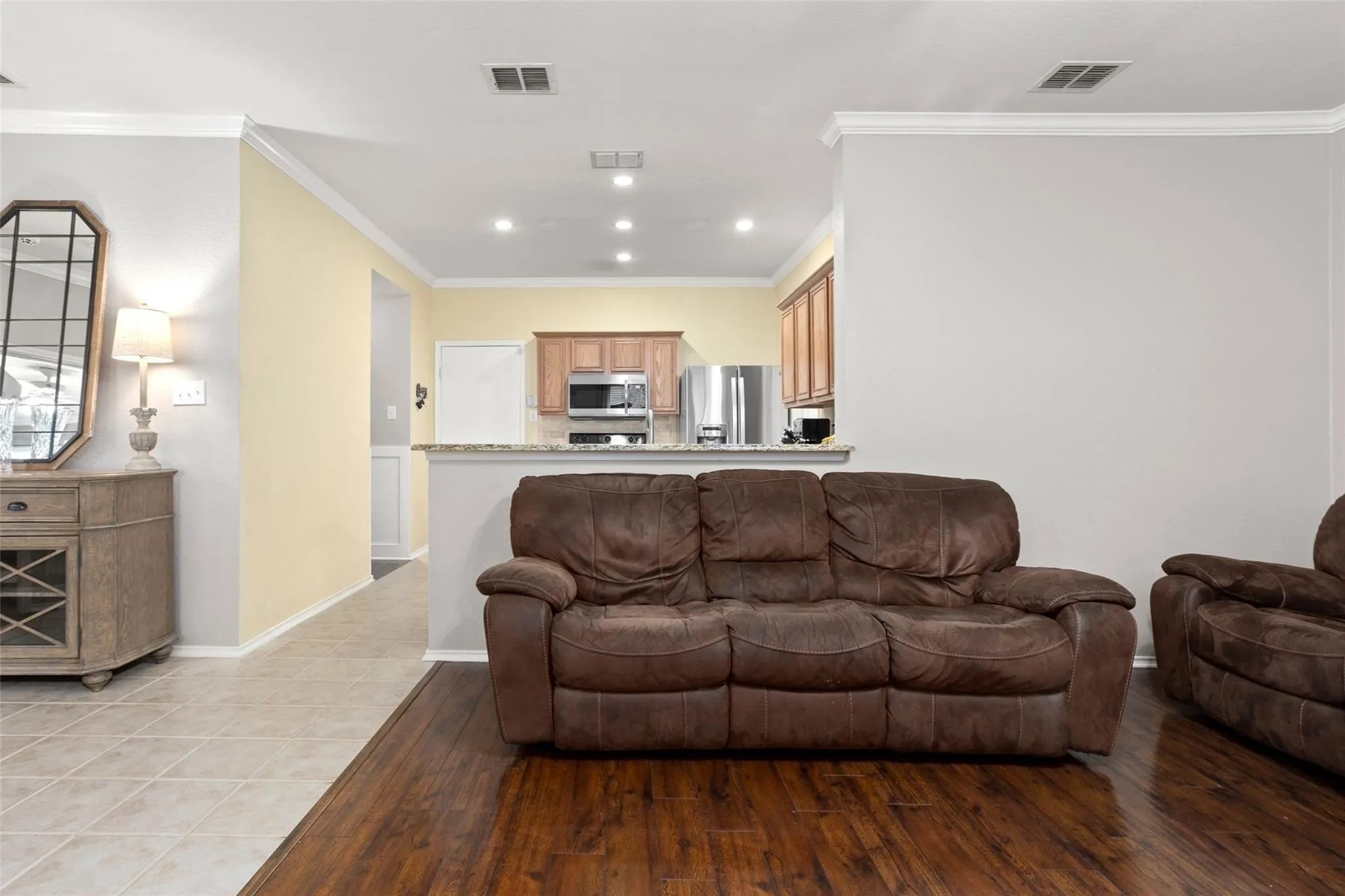 Wood-finish flooring, recessed lighting, crown molding, kitchen with wood cabinetry, and stainless steel appliances