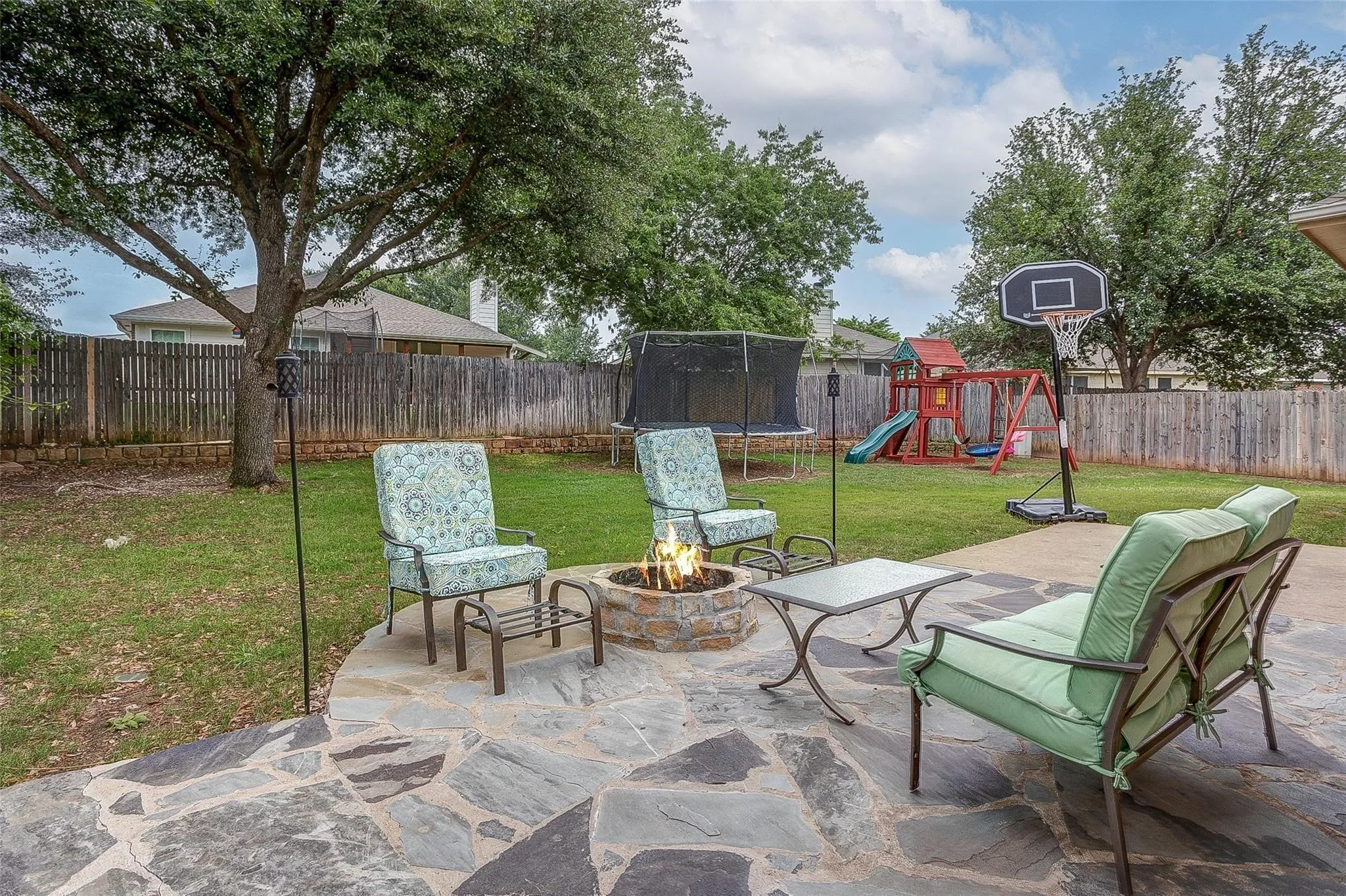 Expansive backyard featuring a stone fire pit, flagstone patio, and mature trees