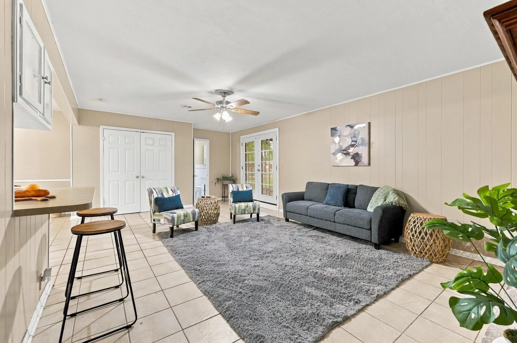 Tiled flooring throughout,  with integrated lighting, wood paneling on walls, and white French doors