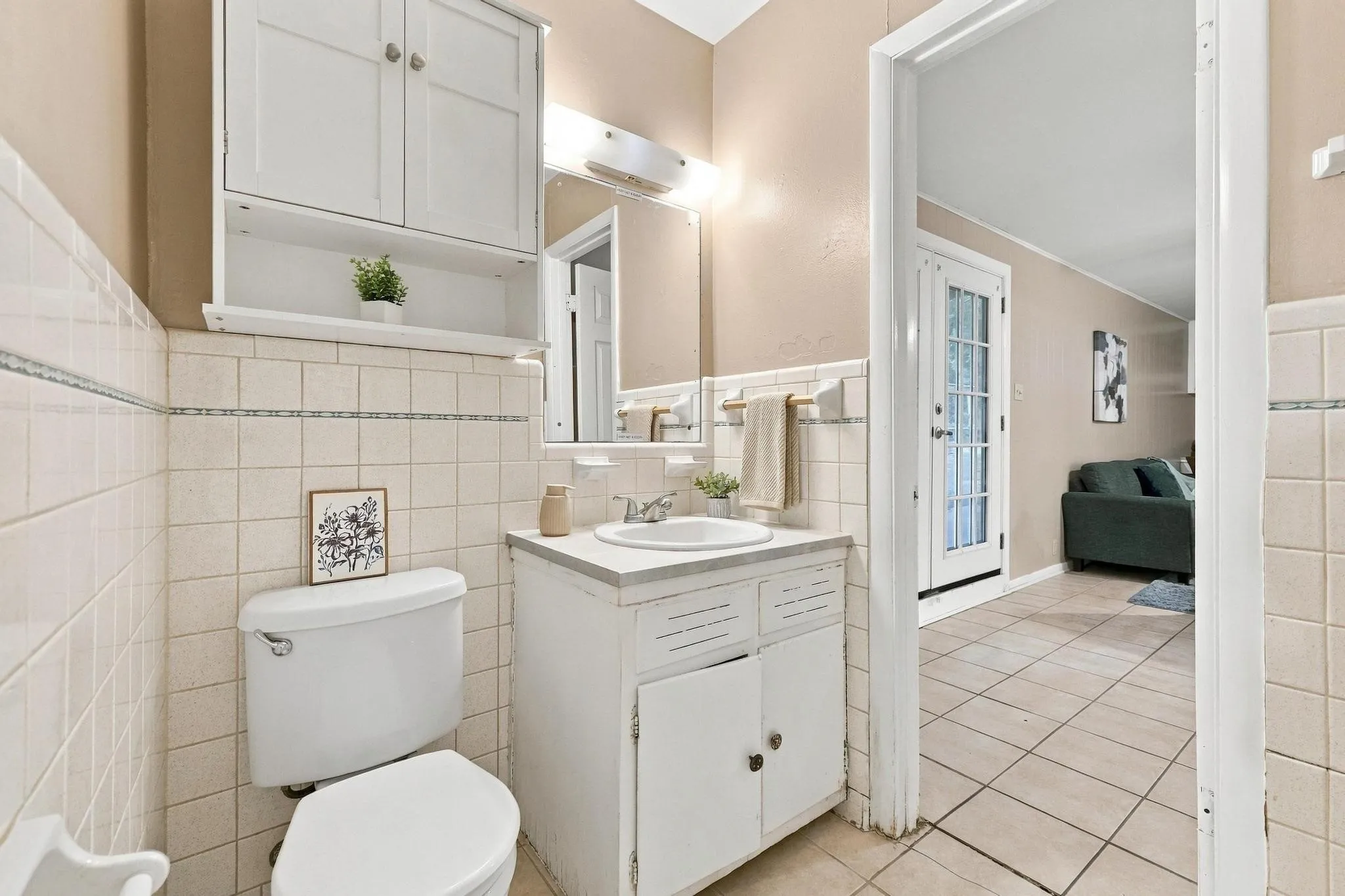 Bathroom featuring a white vanity with a built-in sink, white wall-mounted cabinetry, and tiled walls