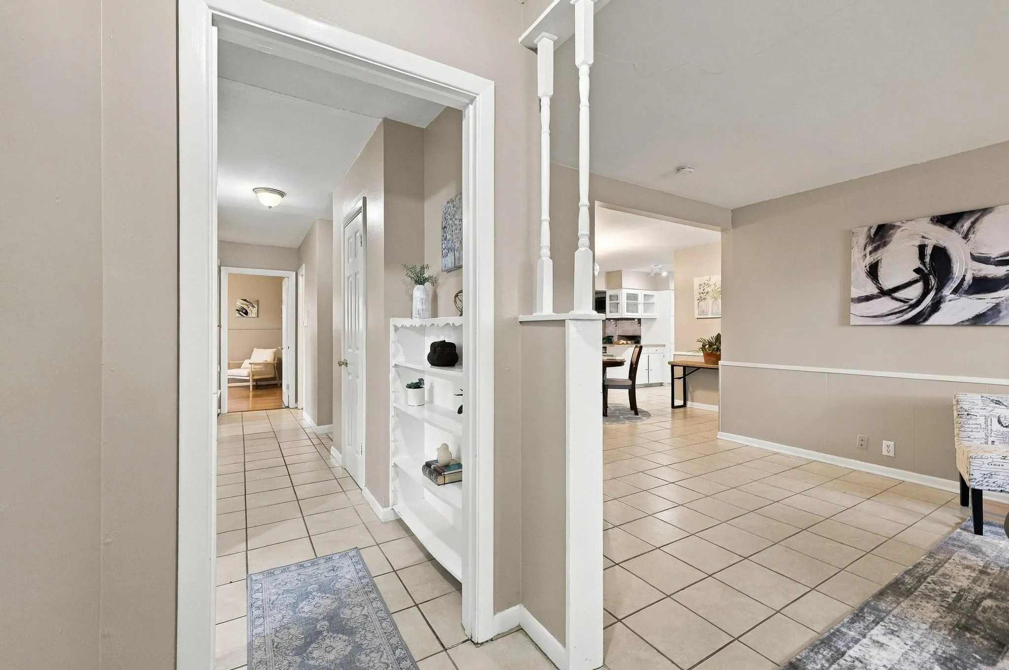 Tiled flooring throughout the main entry, complete with a built-in shelving unit, white trim, and neutral wall paint