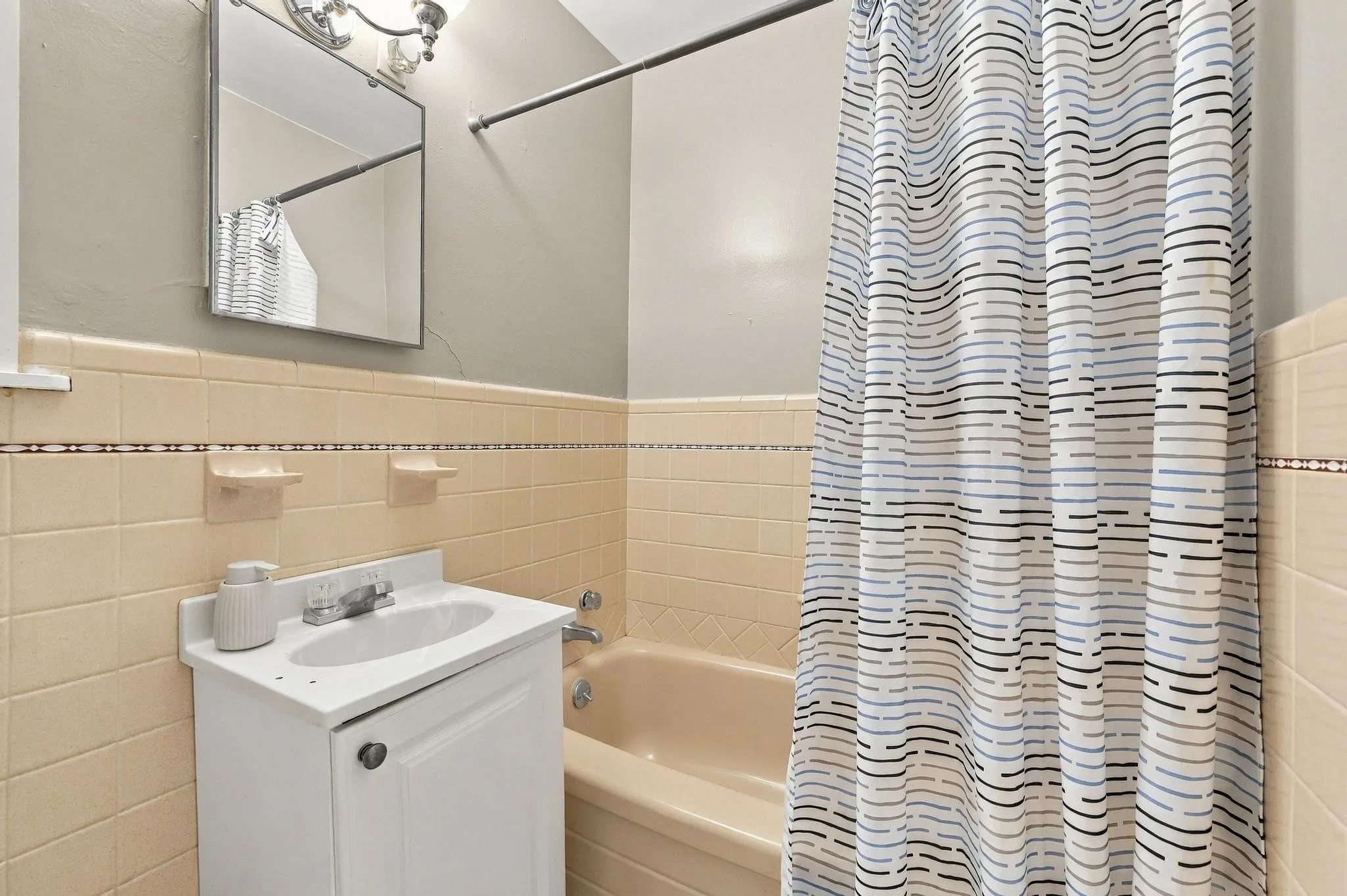 Bathroom featuring a built-in bathtub, a vanity with an integrated sink, and ceramic wall tiling