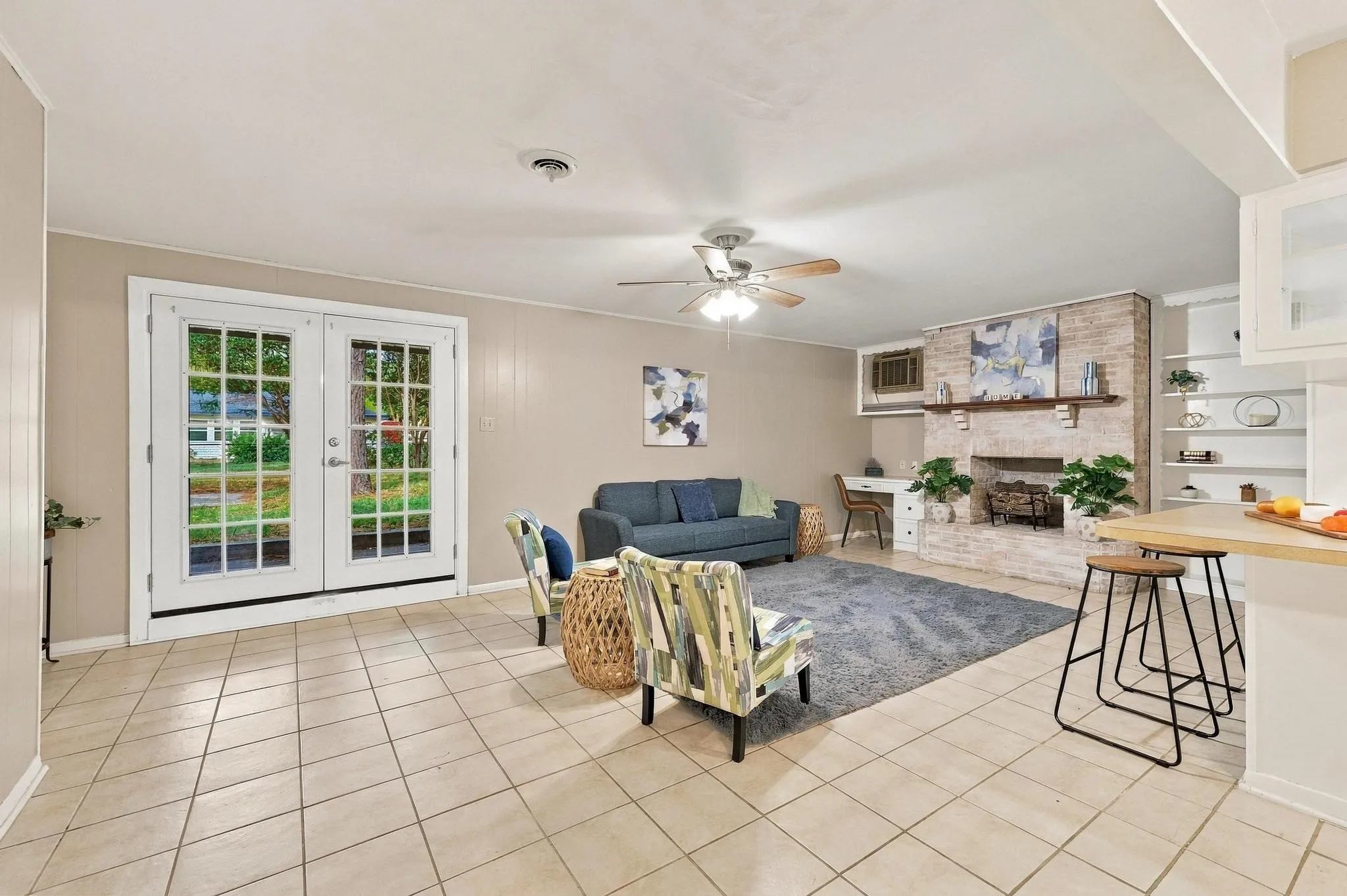 Tiled flooring throughout, white French doors, brick fireplace with wood mantel