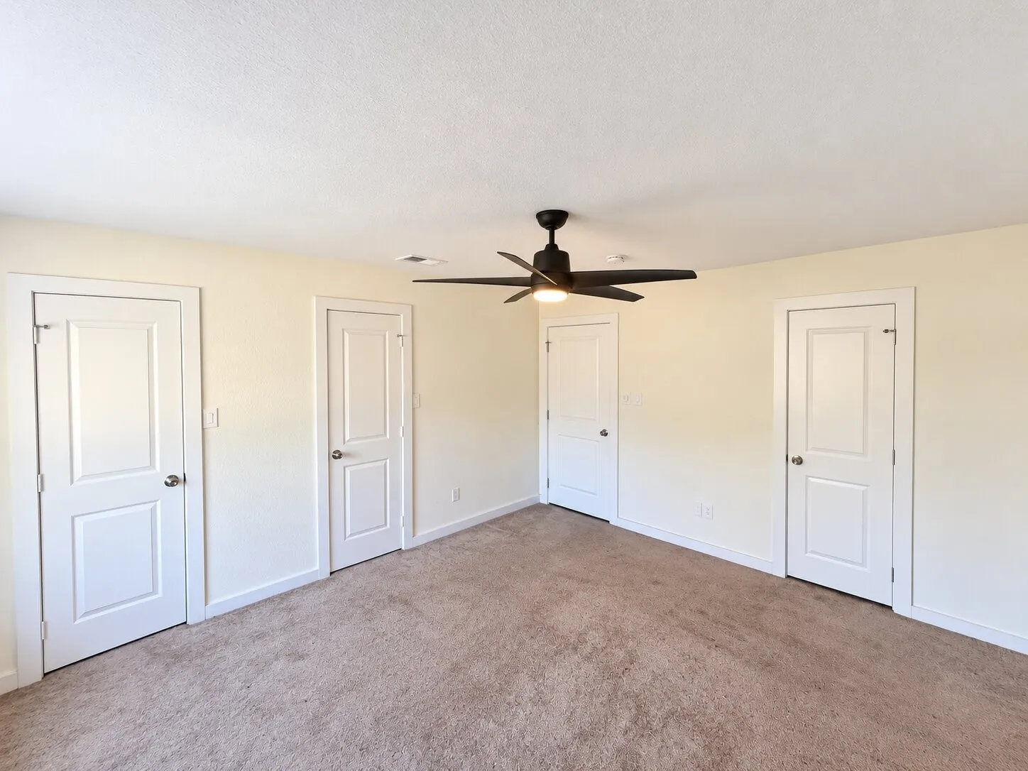 Neutral tone wall finishes, white trim, and a black ceiling fan with integrated lighting