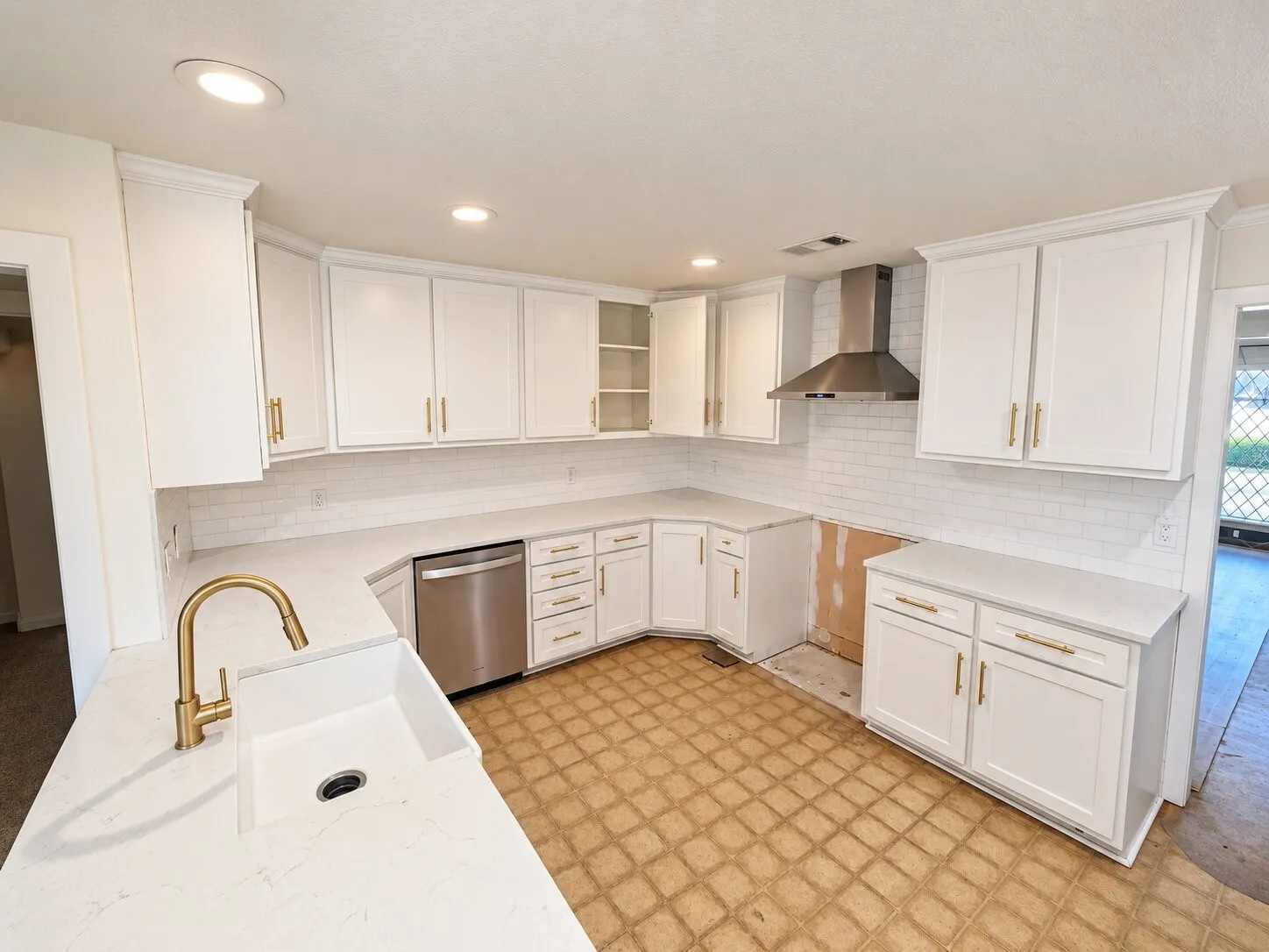 White cabinetry with gold-finish hardware, stainless steel appliances, white subway tile backsplash, recessed lighting, and a gold-finish kitchen faucet