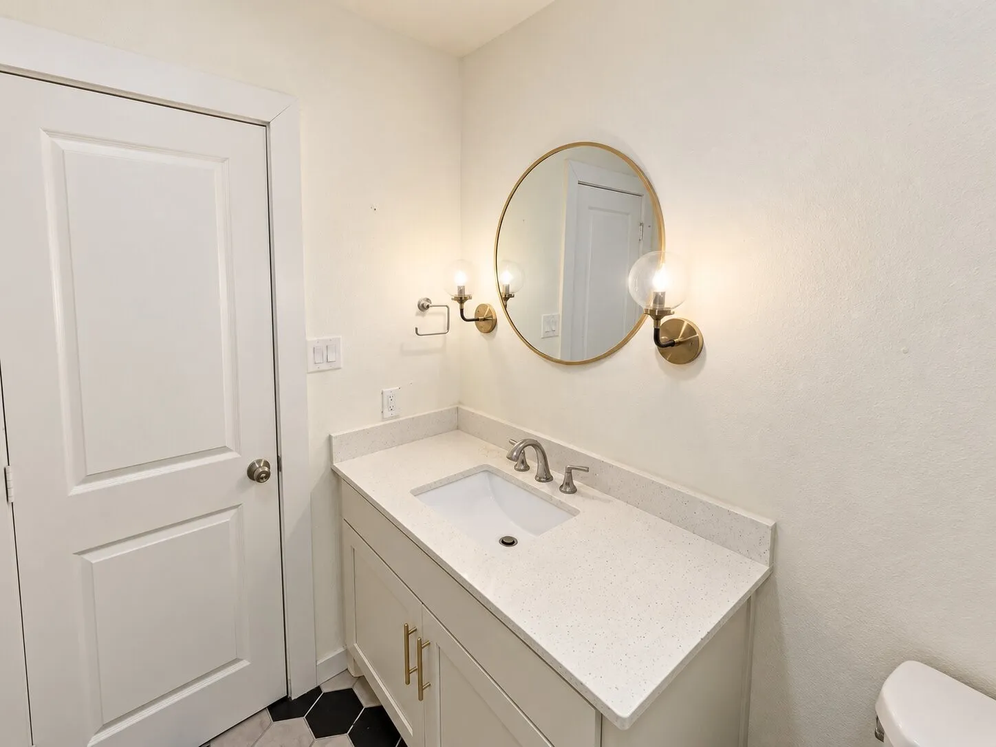Vanity with integrated sink, light-toned countertop, and gold-finish hardware