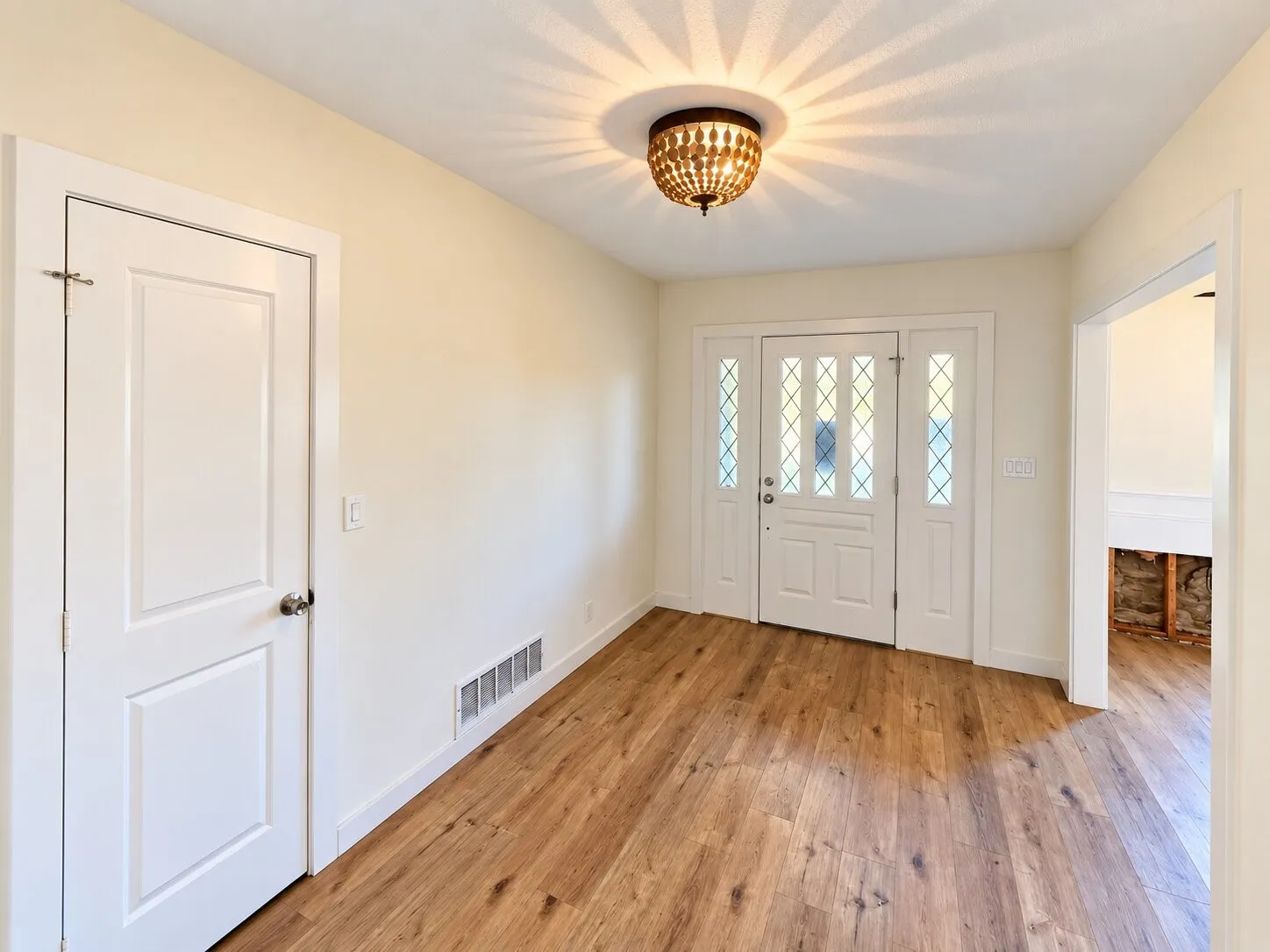 Entryway featuring wood-finish flooring, a decorative semi-flush mount light fixture, white trim, and a white paneled door