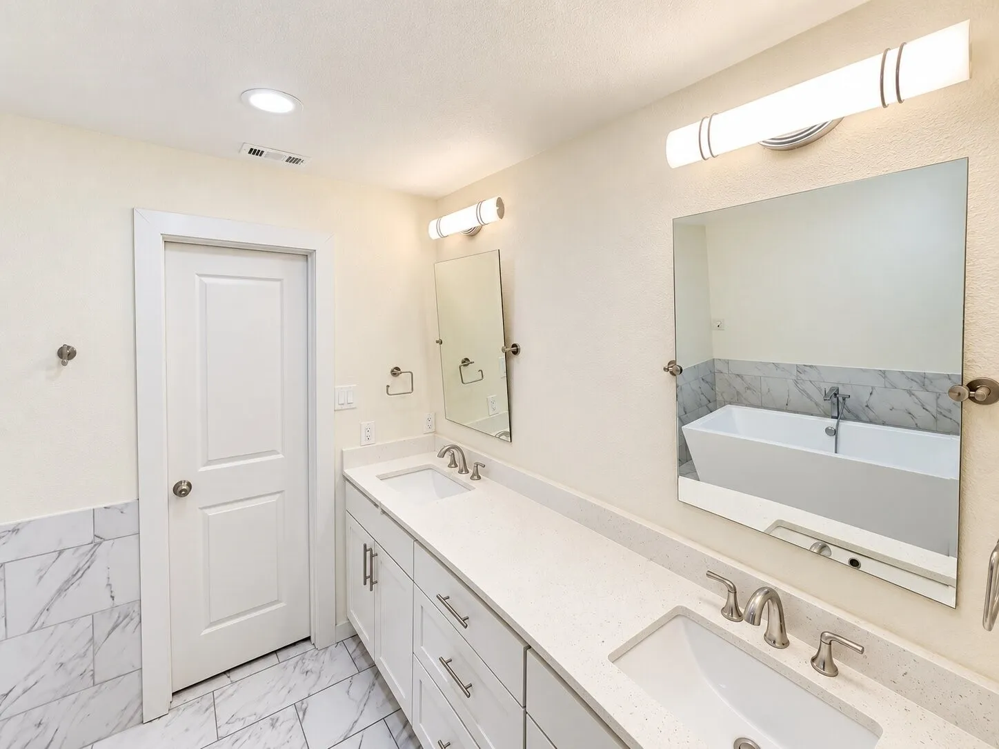 Dual vanity with undermount sinks, stone-look countertops, white cabinetry, and brushed nickel hardware