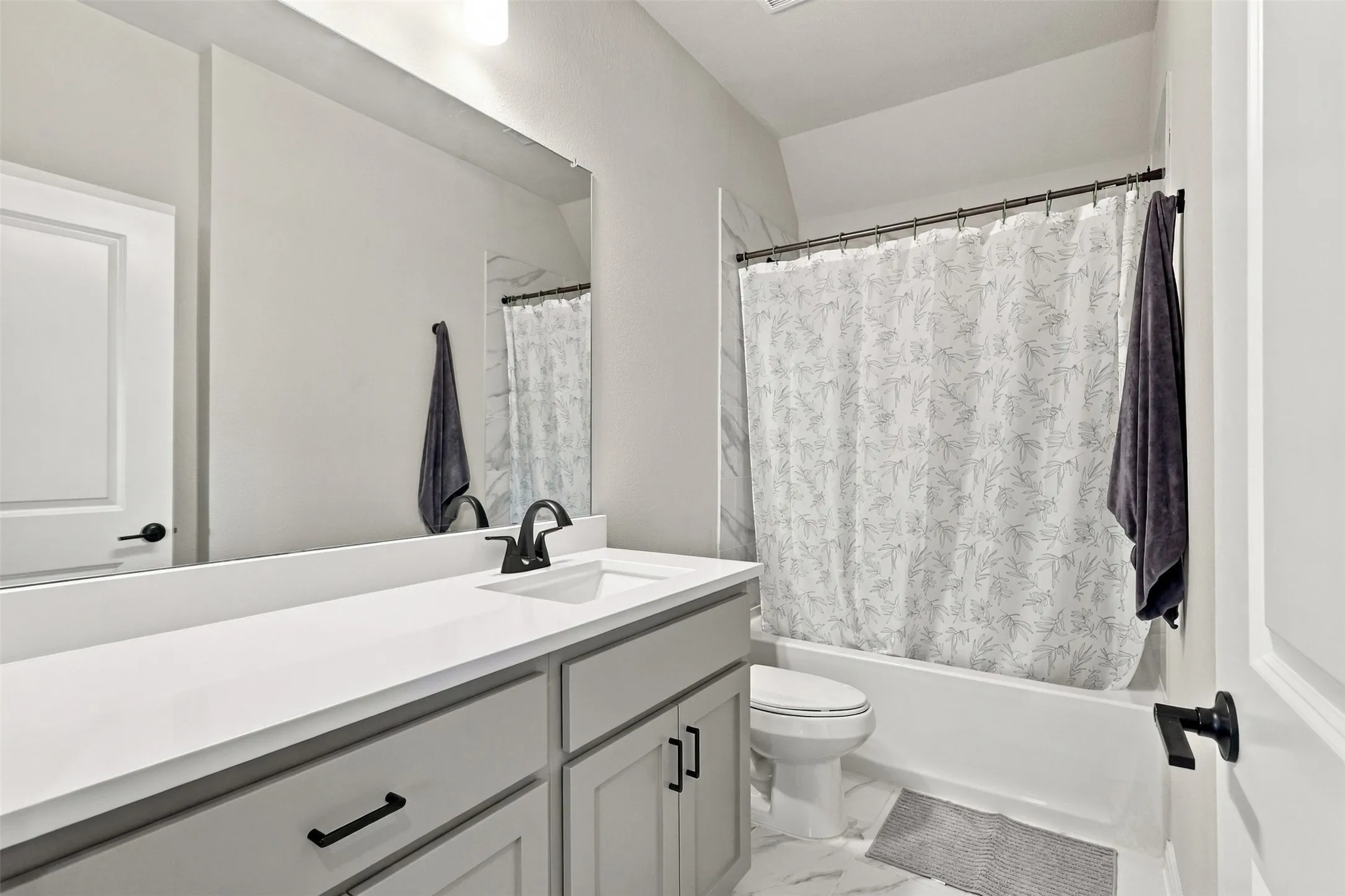 Bathroom featuring a vanity with an integrated sink, black fixtures, and a shower-tub combination