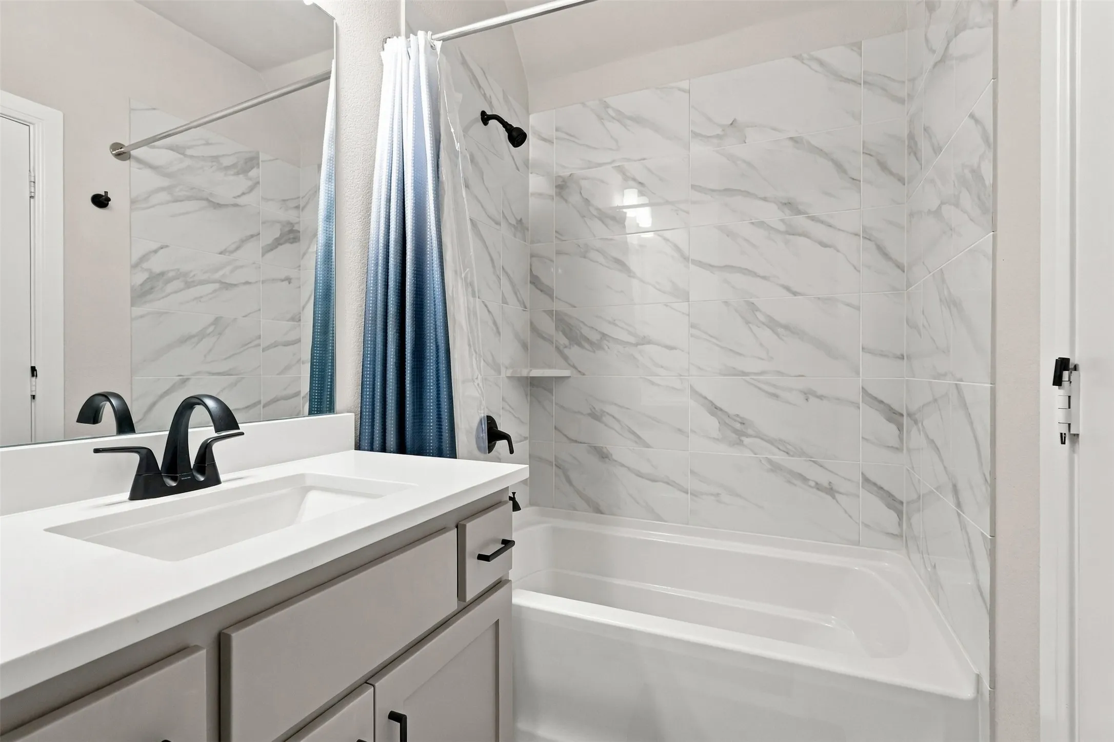 White vanity with a single basin sink, matte black faucet, and cabinet storage