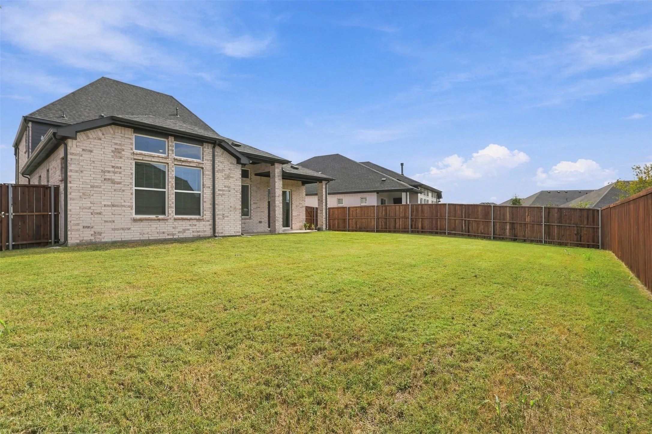 Expansive backyard featuring a privacy fence and a brick-clad exterior
