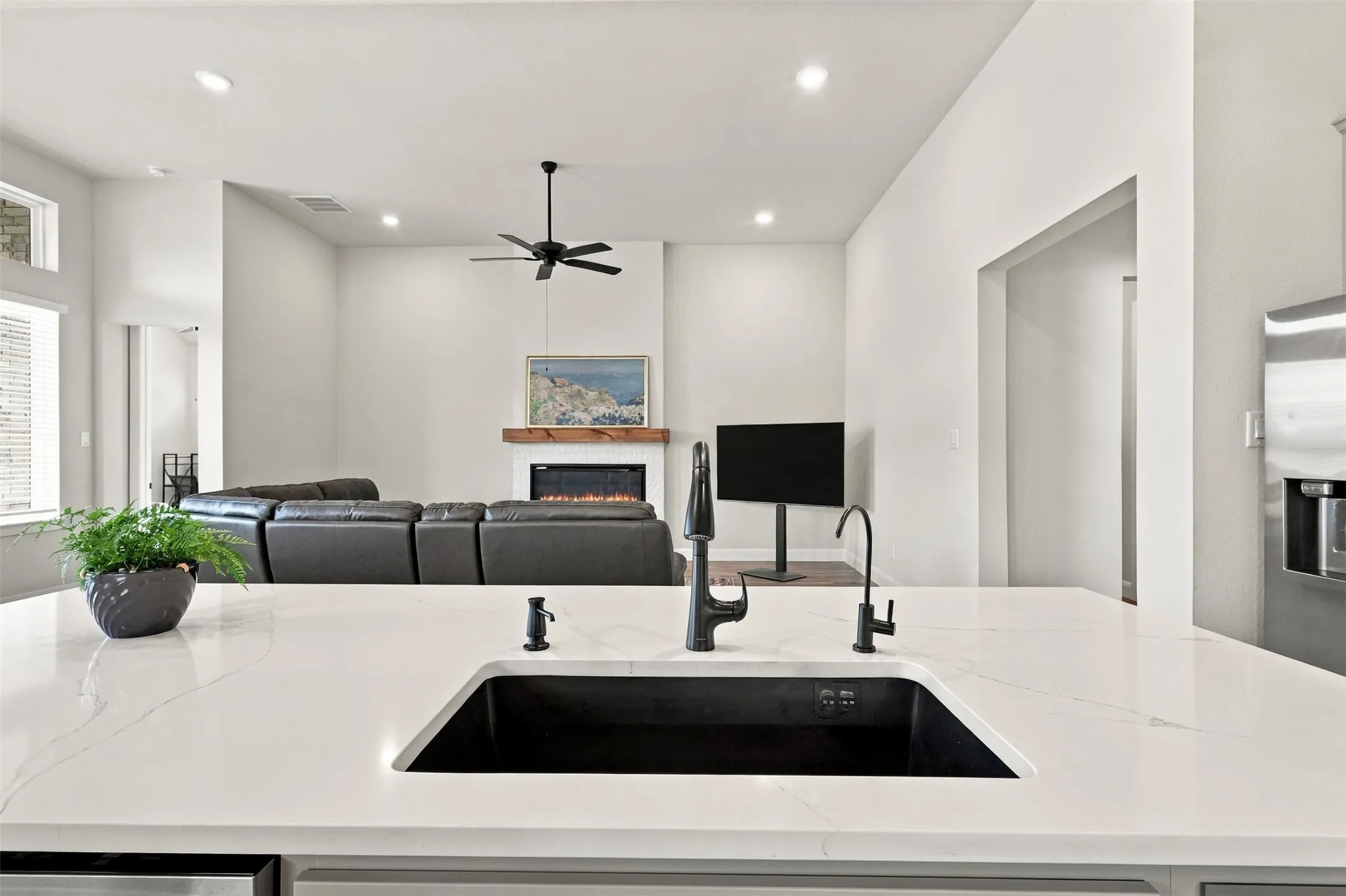 Kitchen island with a black undermount sink, gooseneck faucet, and light-toned countertop