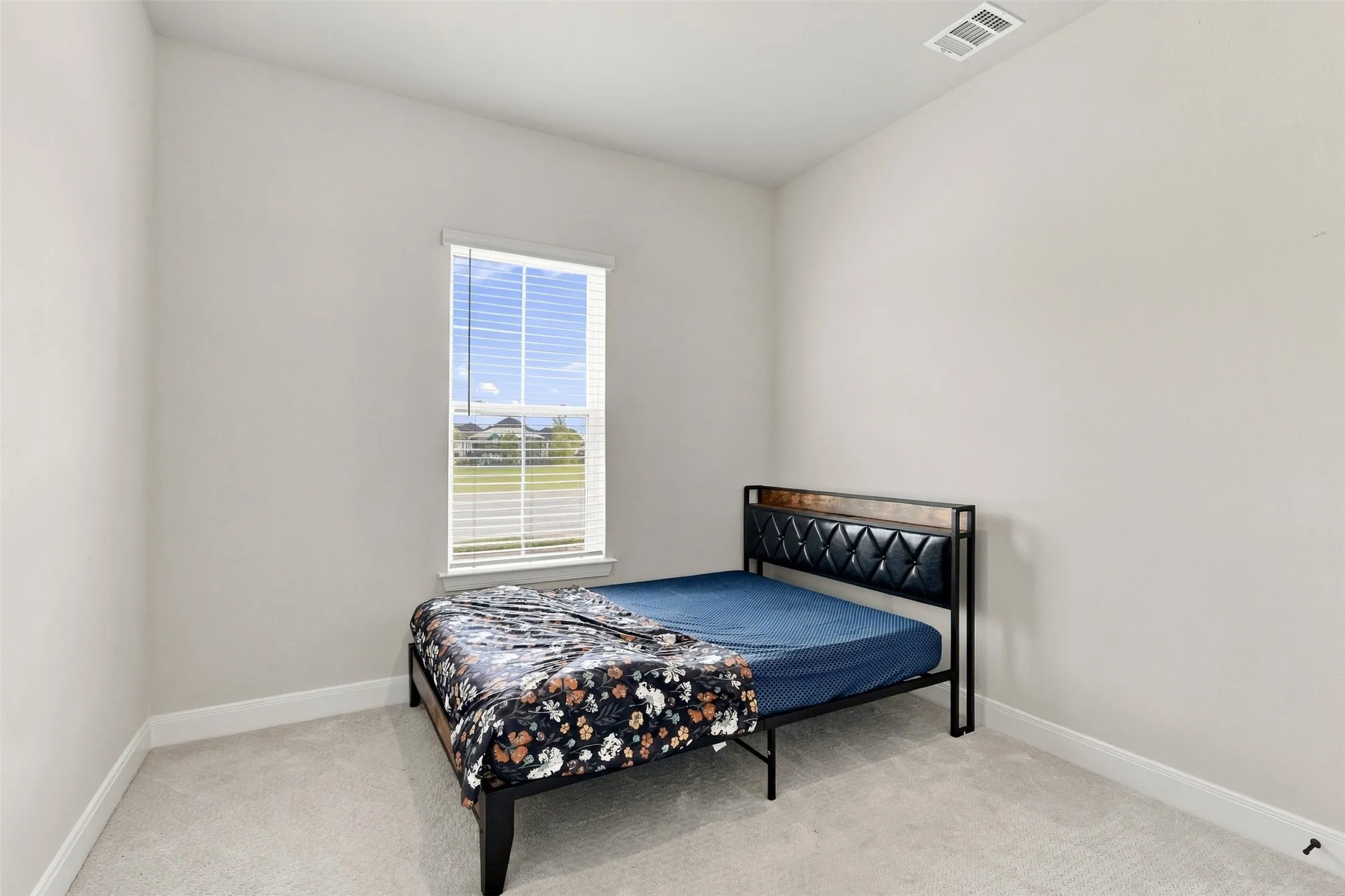 Light gray wall paint, single window with blinds, light gray carpeting, and white trim