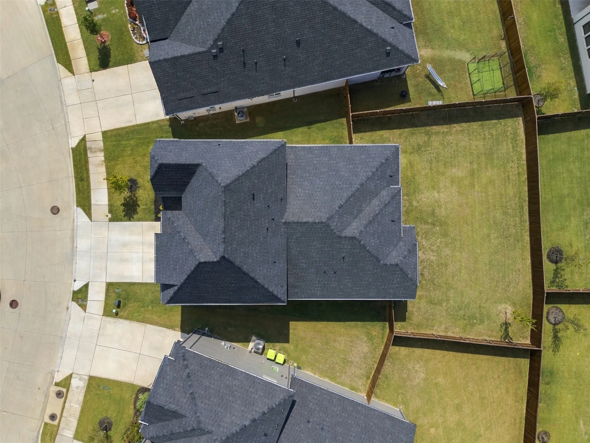 Pitched shingle roof, paved driveway, concrete sidewalks, and fenced rear yard