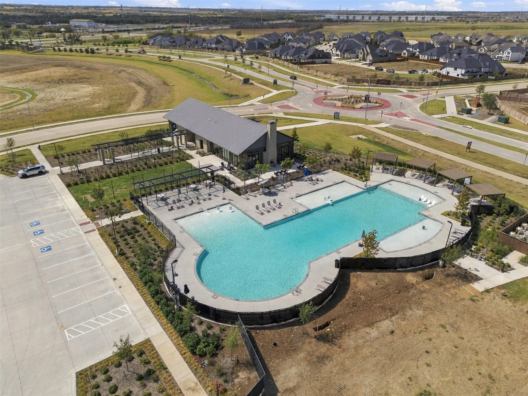 Expansive outdoor pool area with multiple lounge spaces, a large main pool, and a recreational building with an attached covered patio
