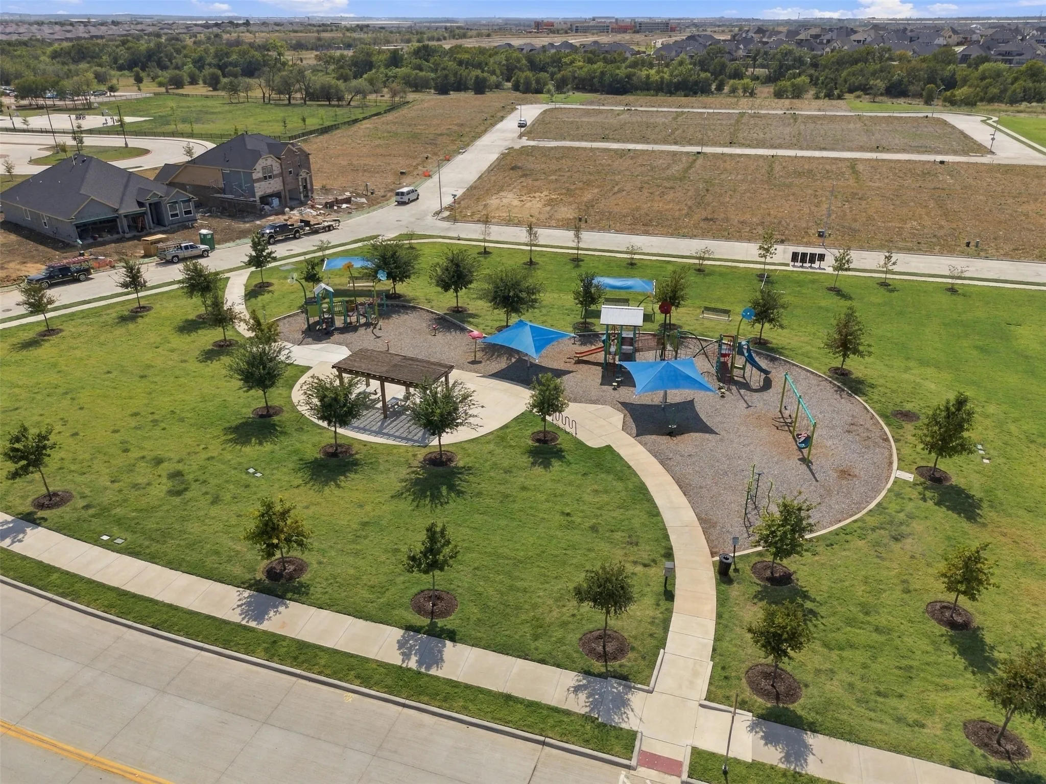 Community park featuring a playground with shade structures, a pergola, and walking paths