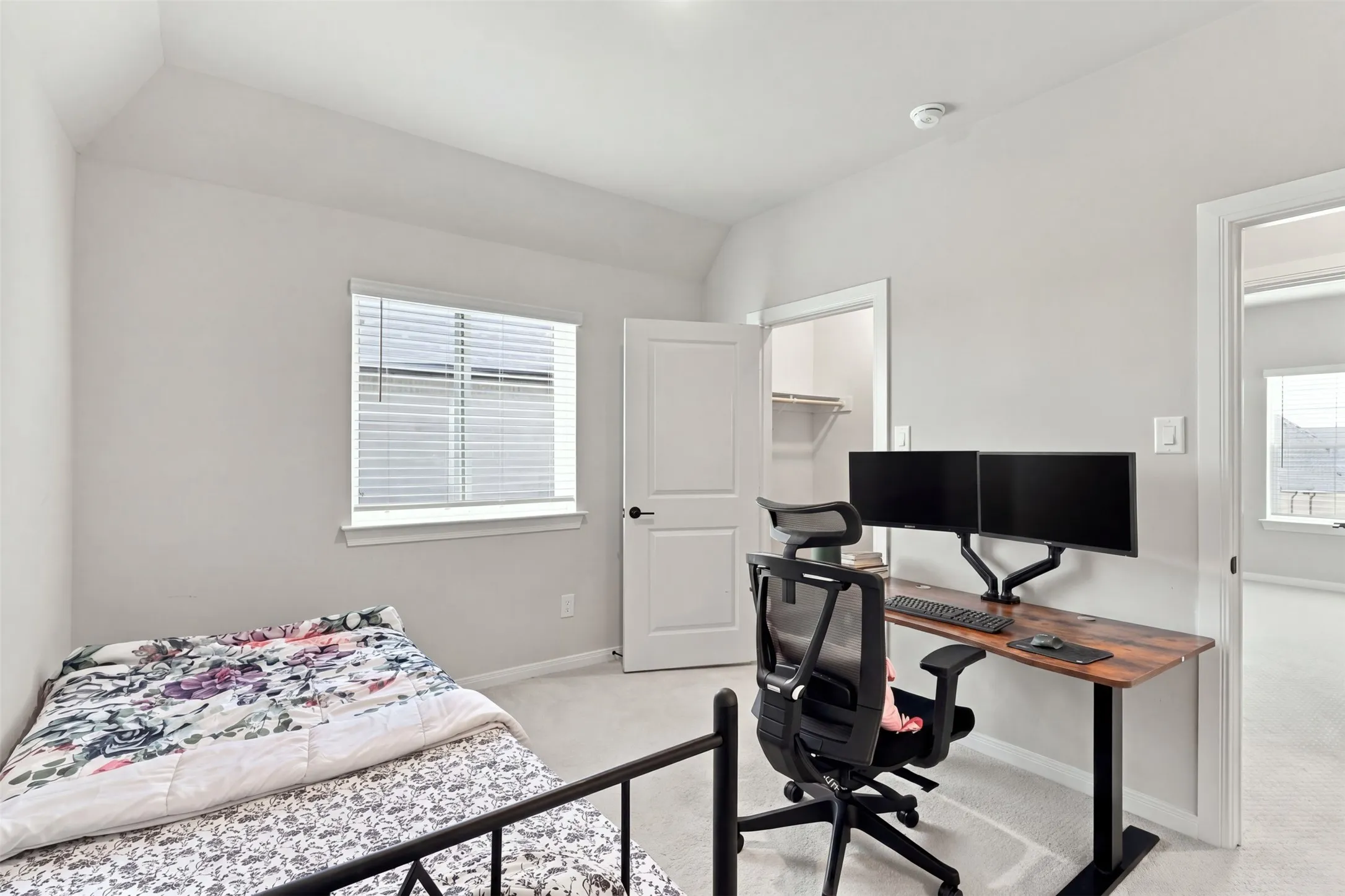 Carpeted room with a window, white interior door, and built-in closet shelving