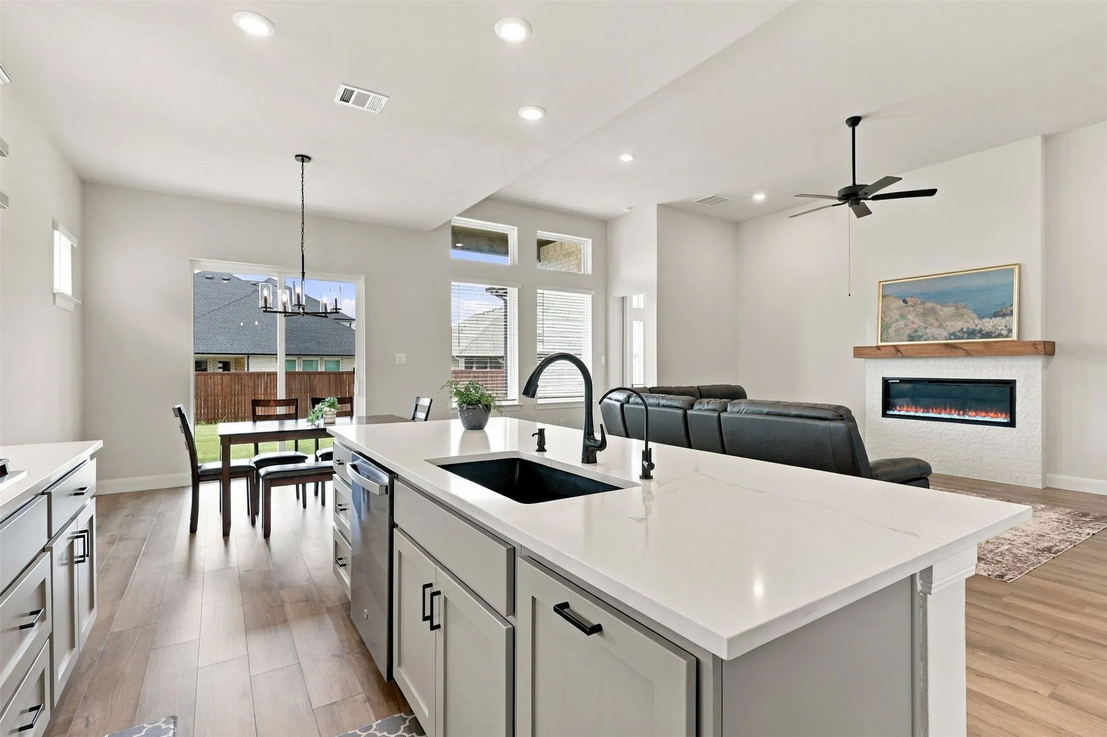 Kitchen island with white countertop, black sink, and matte black faucet