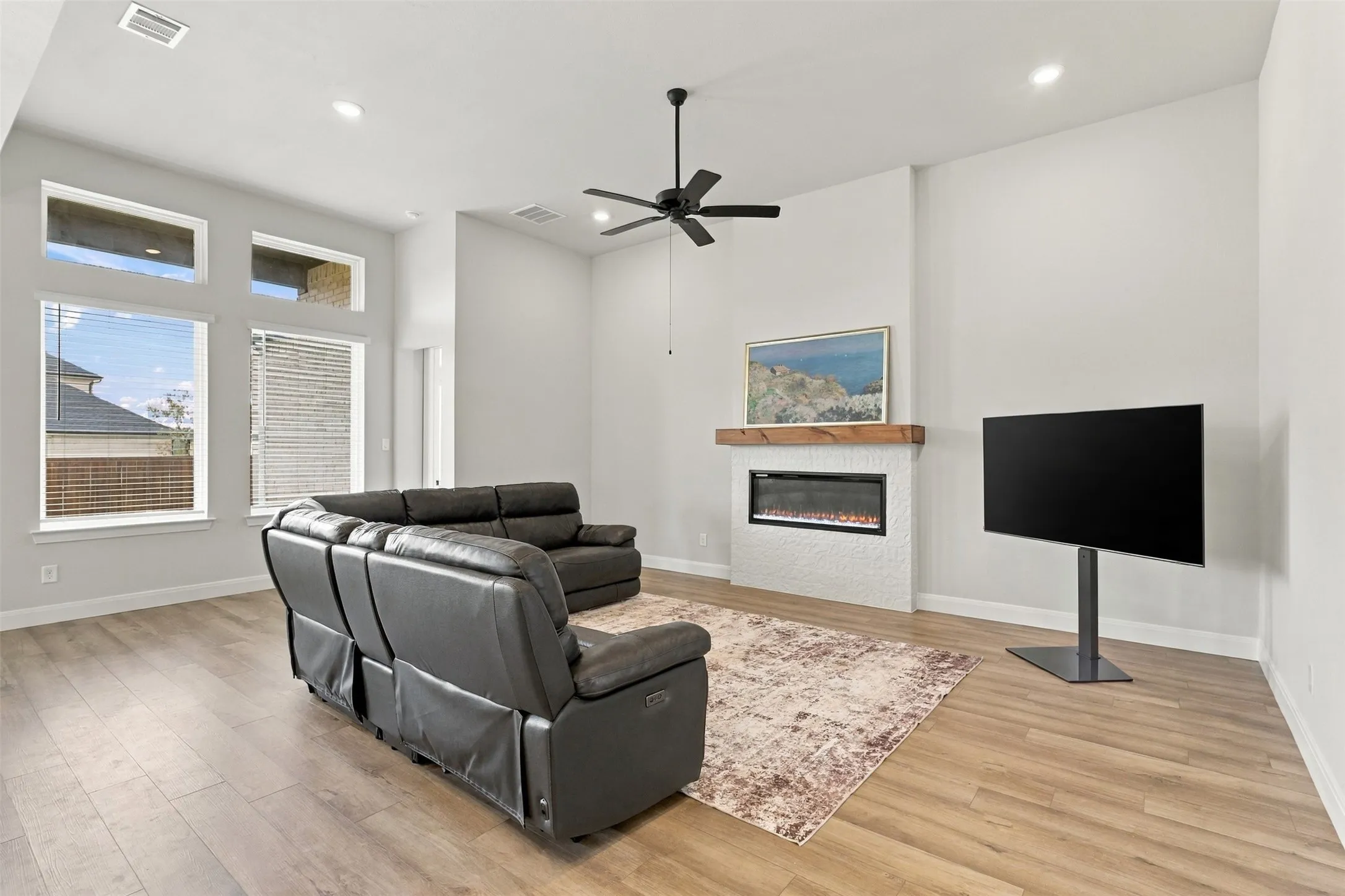 Vaulted ceiling with a ceiling fan, recessed lighting, wood-finish flooring, and multiple windows