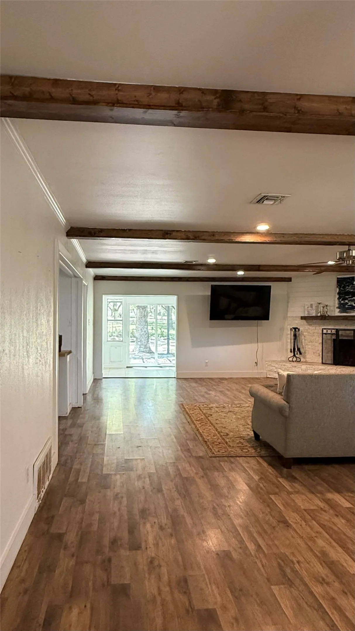 Exposed wood beams, recessed lighting, wood-finish flooring, and white walls create a bright interior