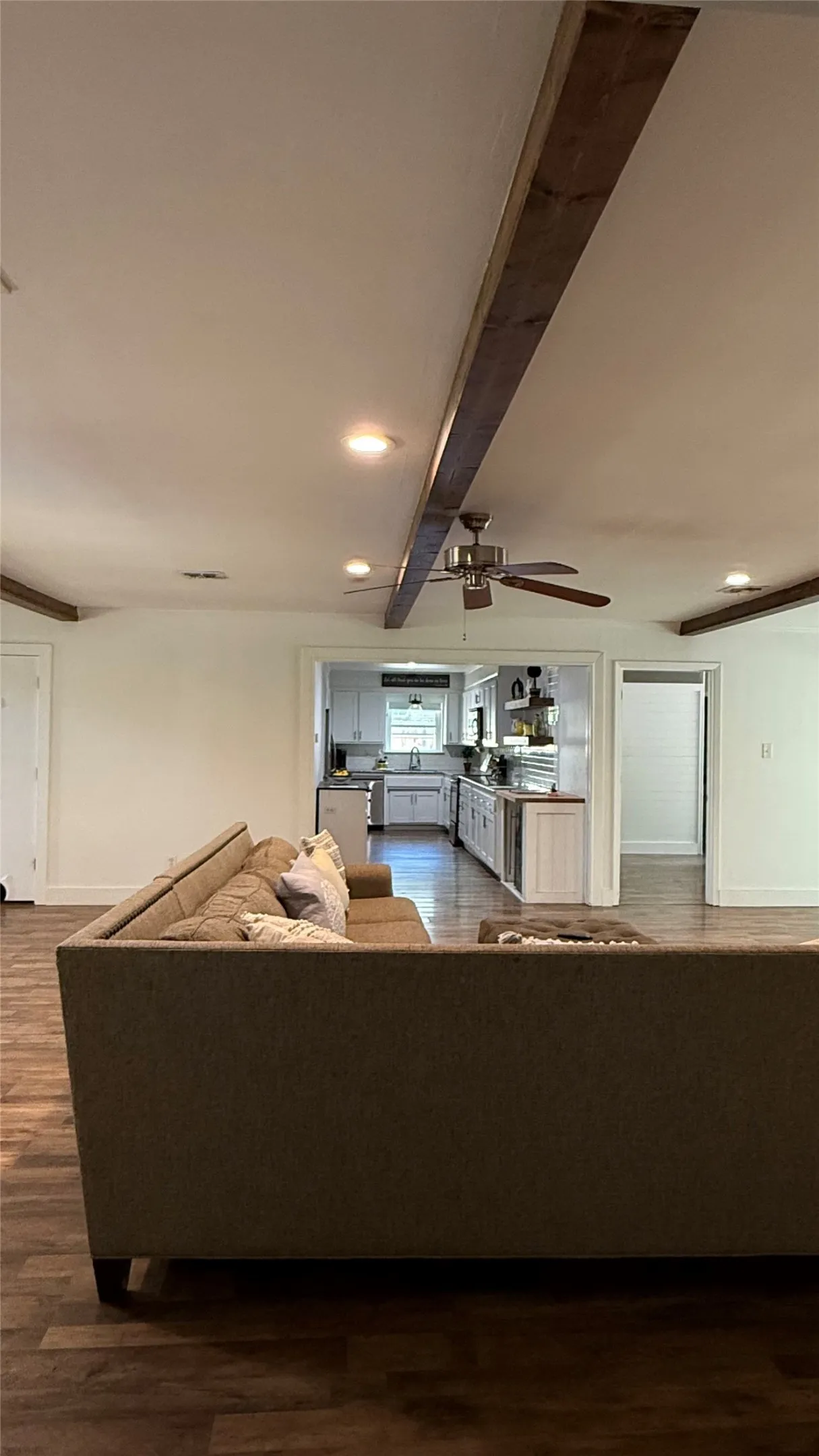 Wood-finish flooring throughout, exposed ceiling beams, recessed lighting, and a ceiling fan