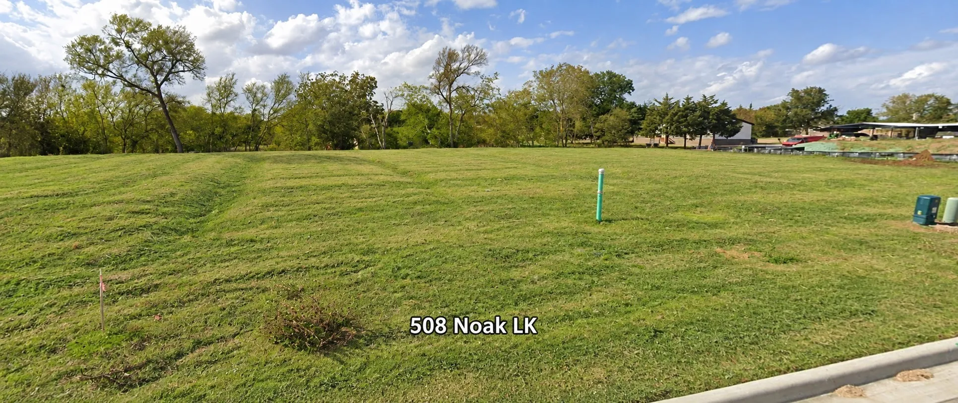 Expansive green lawn with mature trees in the background