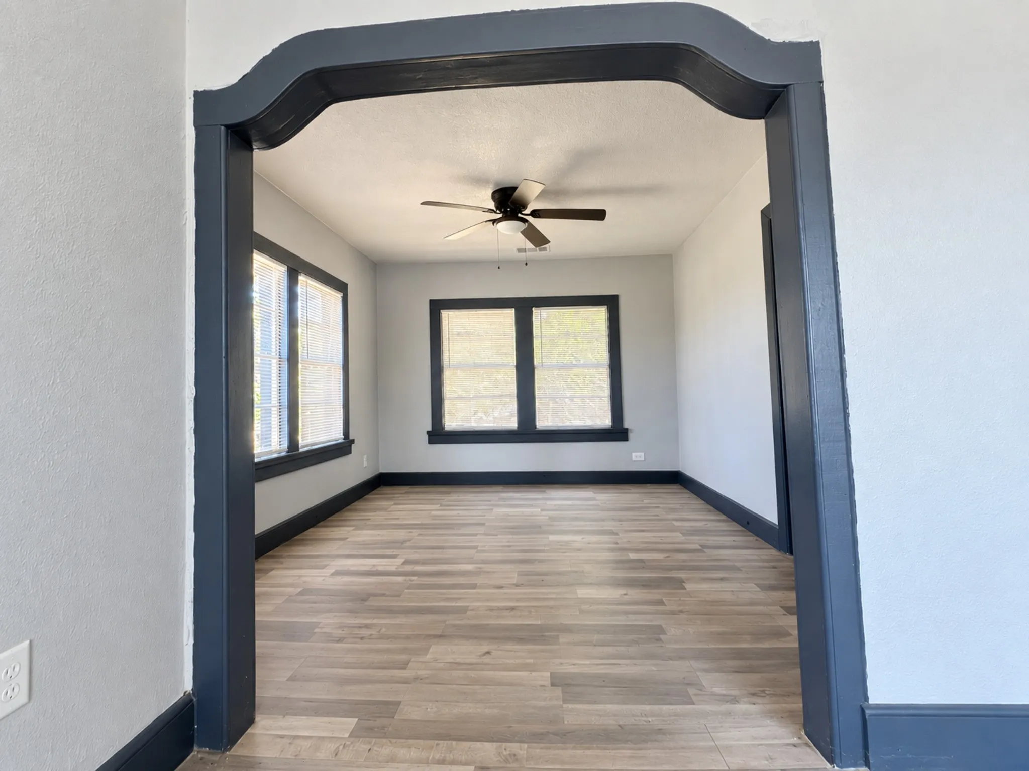 Archway entry into dining area featuring, multiple windows, and a ceiling fan