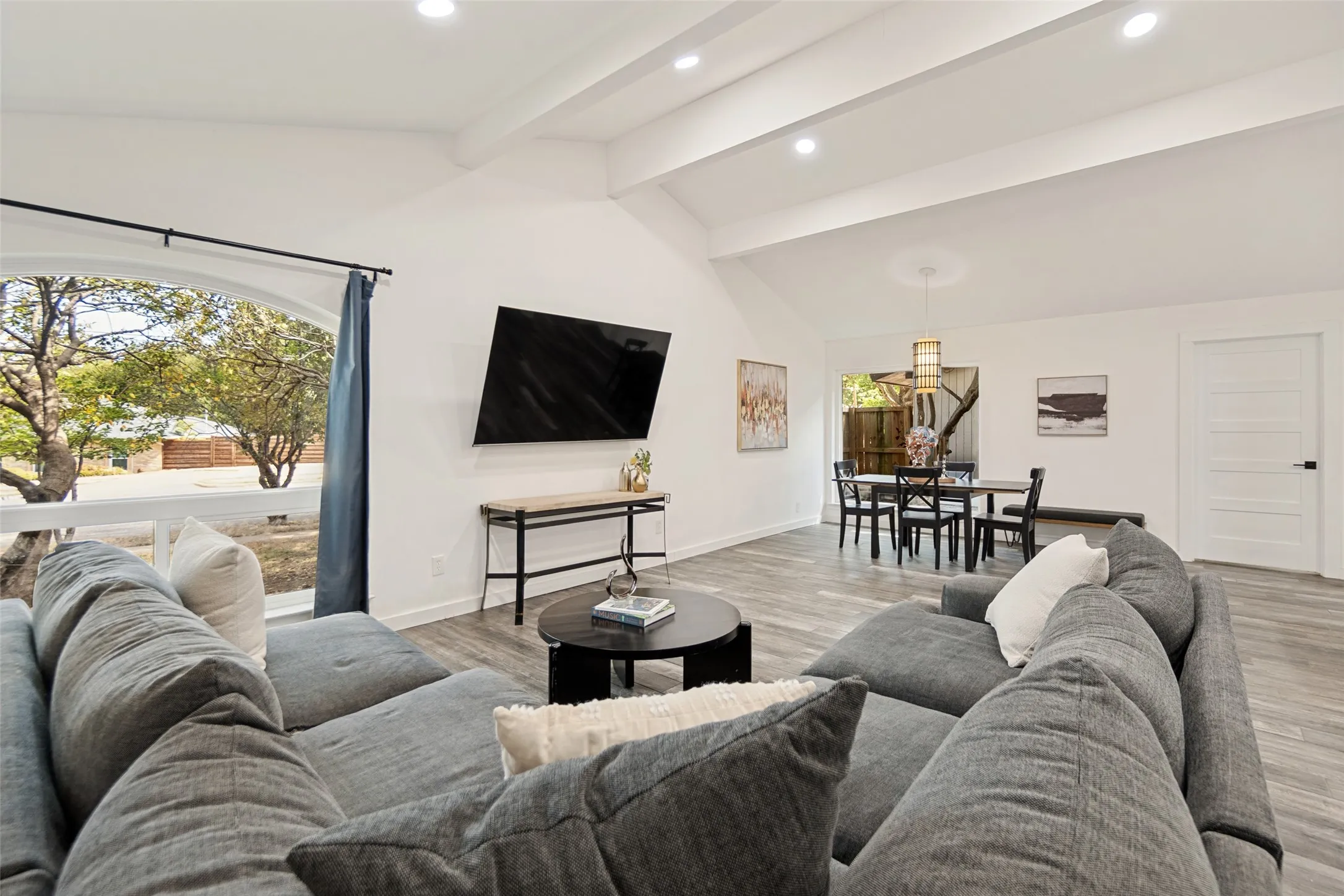 Vaulted ceilings with recessed lighting, wood-finish flooring, and an arched window