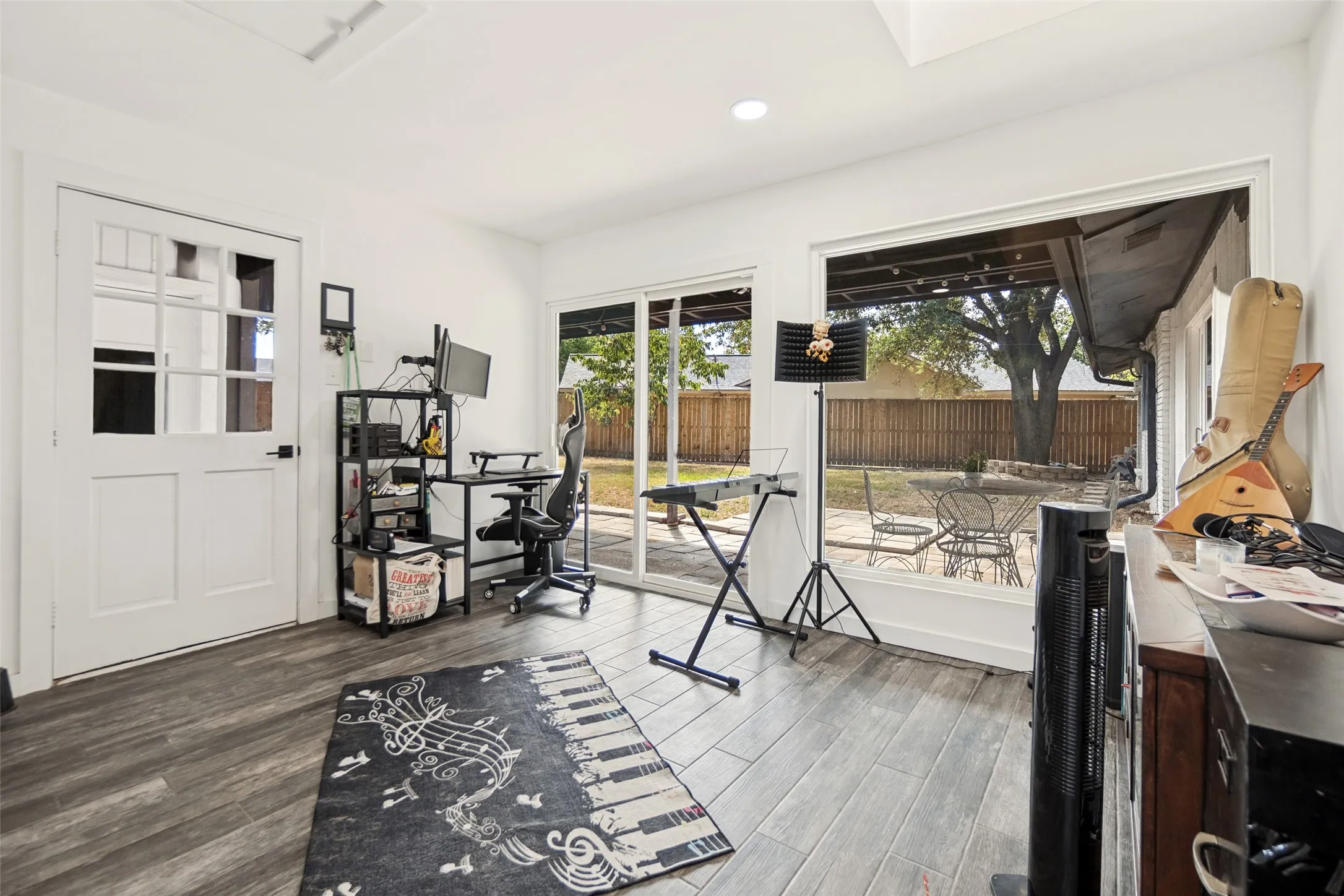 Wood-finish flooring, white paneled French door, large sliding glass door, white walls, and recessed lighting