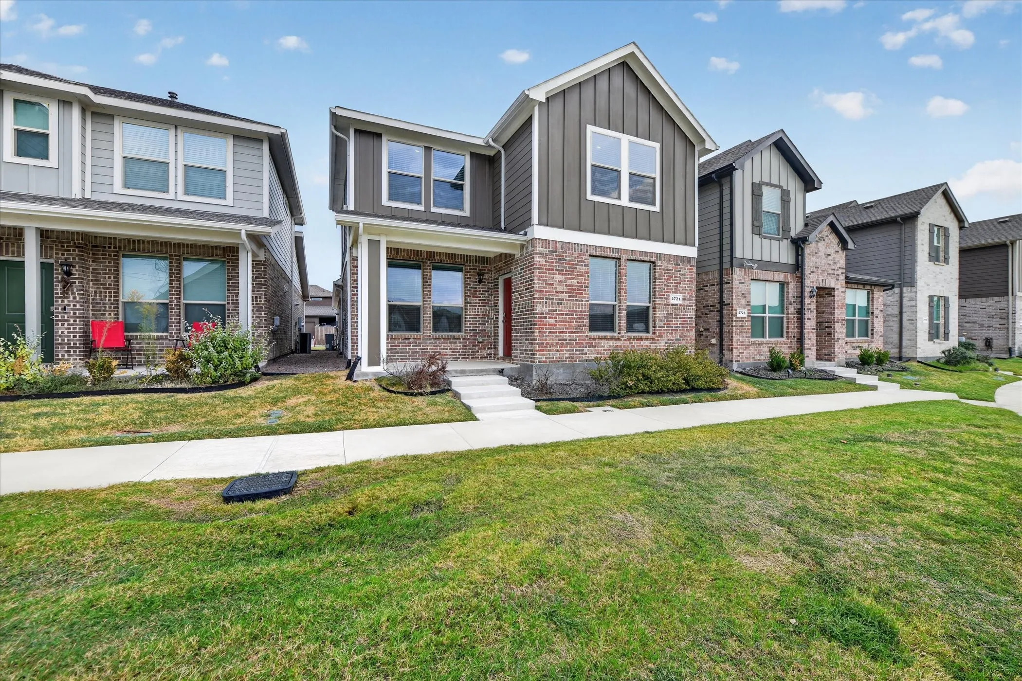 Brick and board-and-batten exterior, multi-story design, attached garage, concrete walkway, landscaped front yard