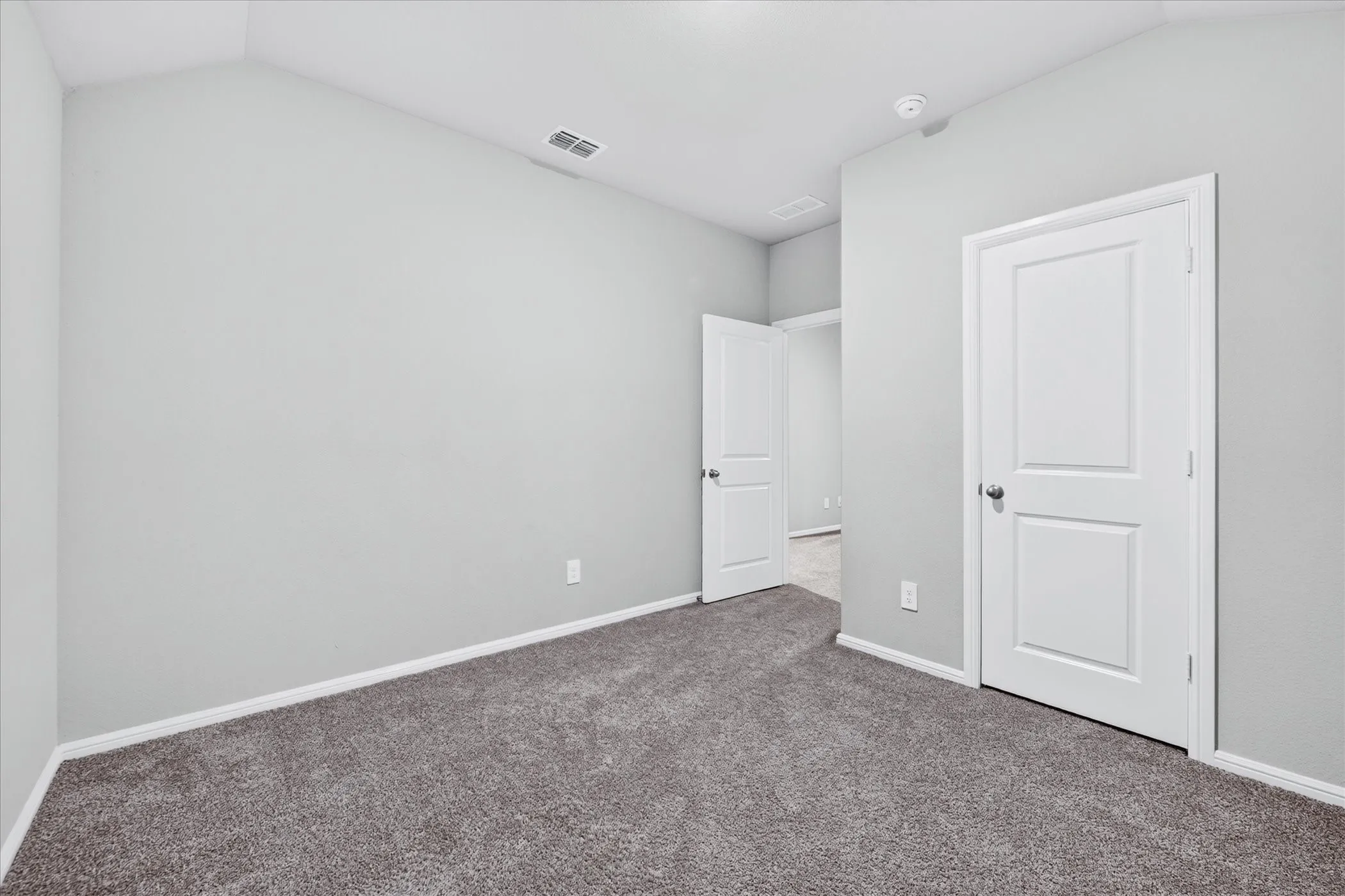 Gray textured carpeting, white baseboards, and light gray wall color