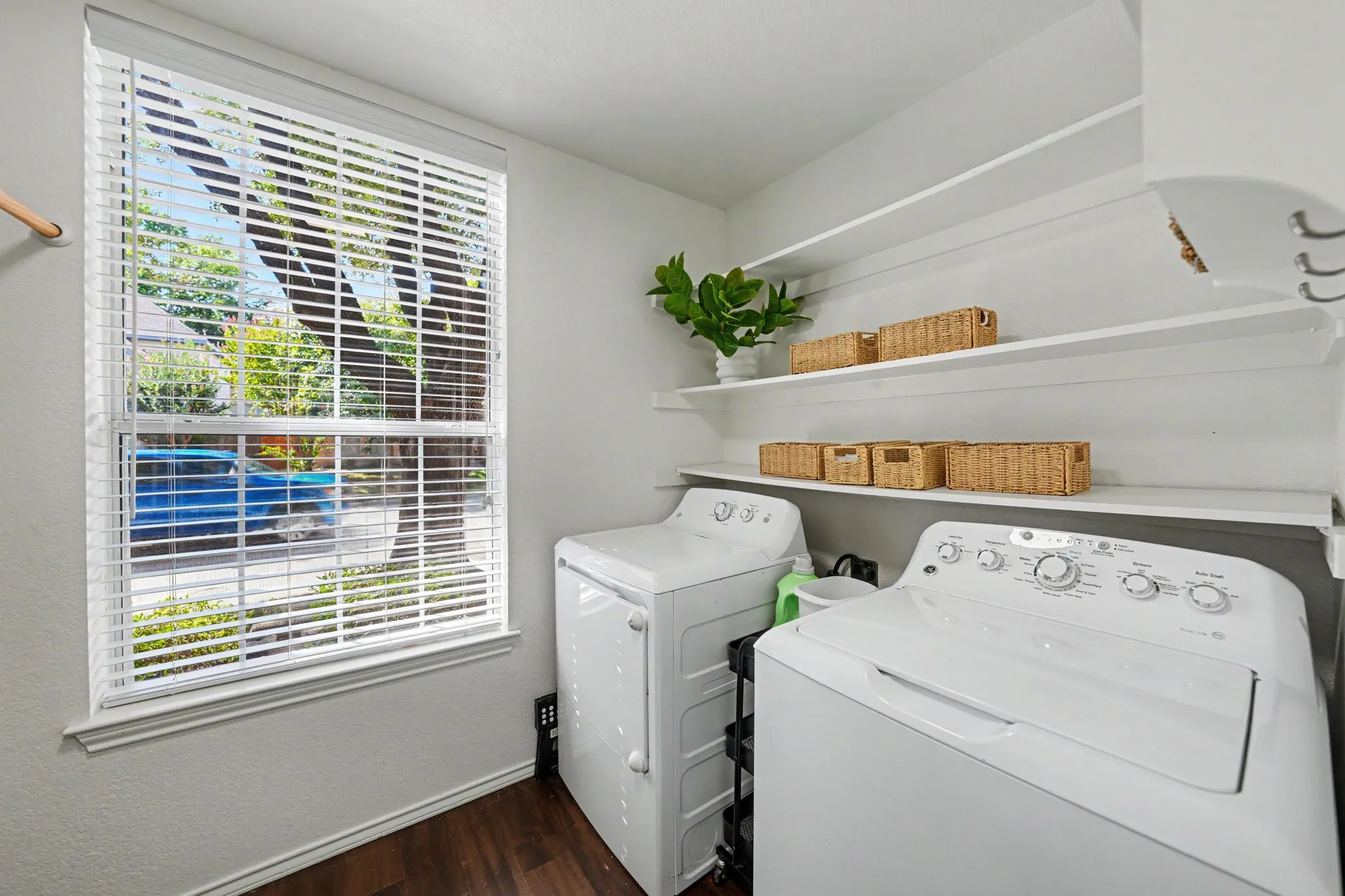 Window with white blinds, wood-finish flooring, and built-in shelving