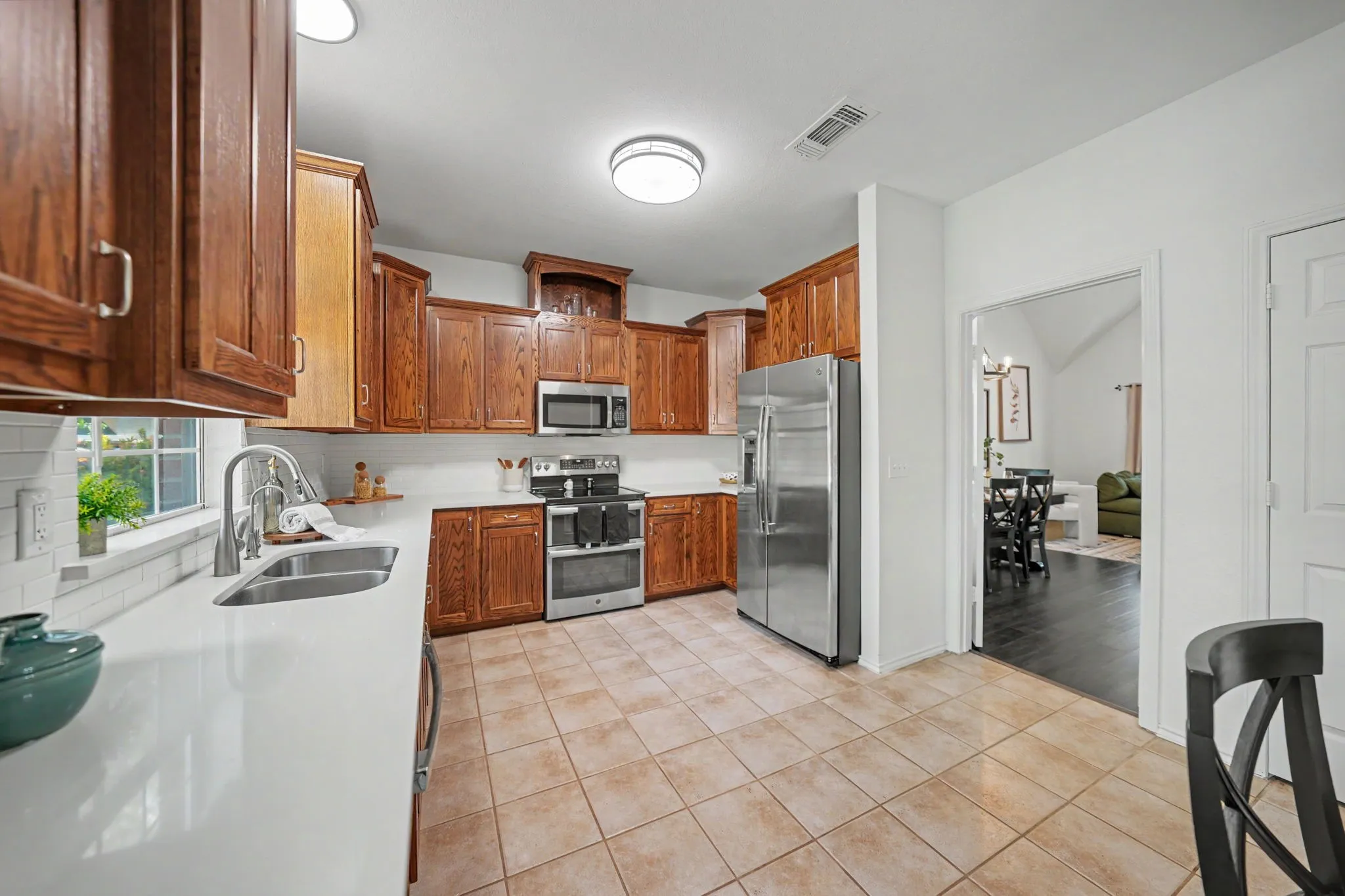 Kitchen featuring wood cabinetry, white countertops, stainless steel appliances, and tile flooring