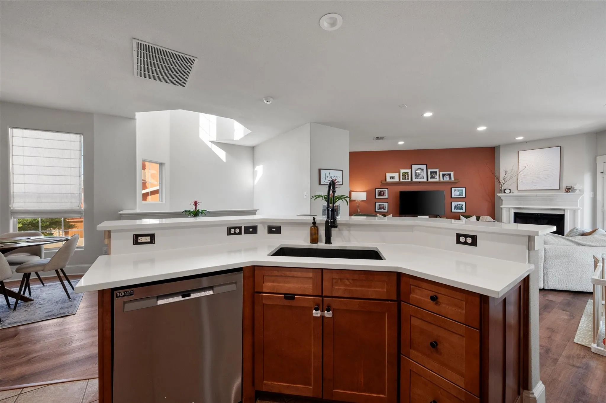 Kitchen featuring a built-in stainless steel dishwasher, an undermount sink with a matte black faucet, and wood-finish cabinetry