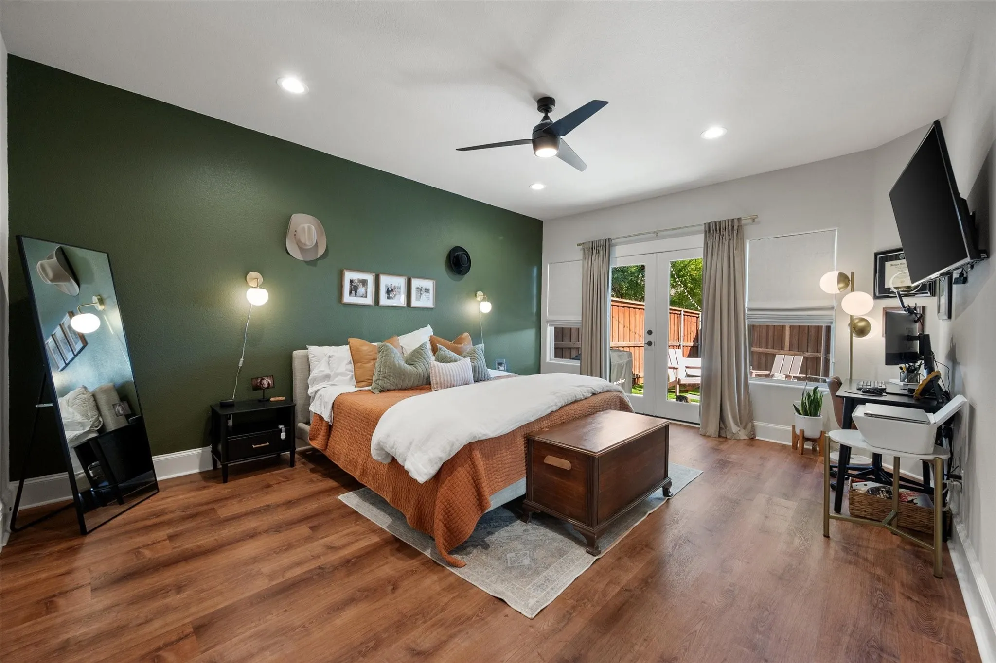 Spacious Primary Bedroom featuring LVP wood like flooring, recessed lighting, modern light + ceiling fan fixture, two large windows and French Doors that lead out to covered back patio in private backyard