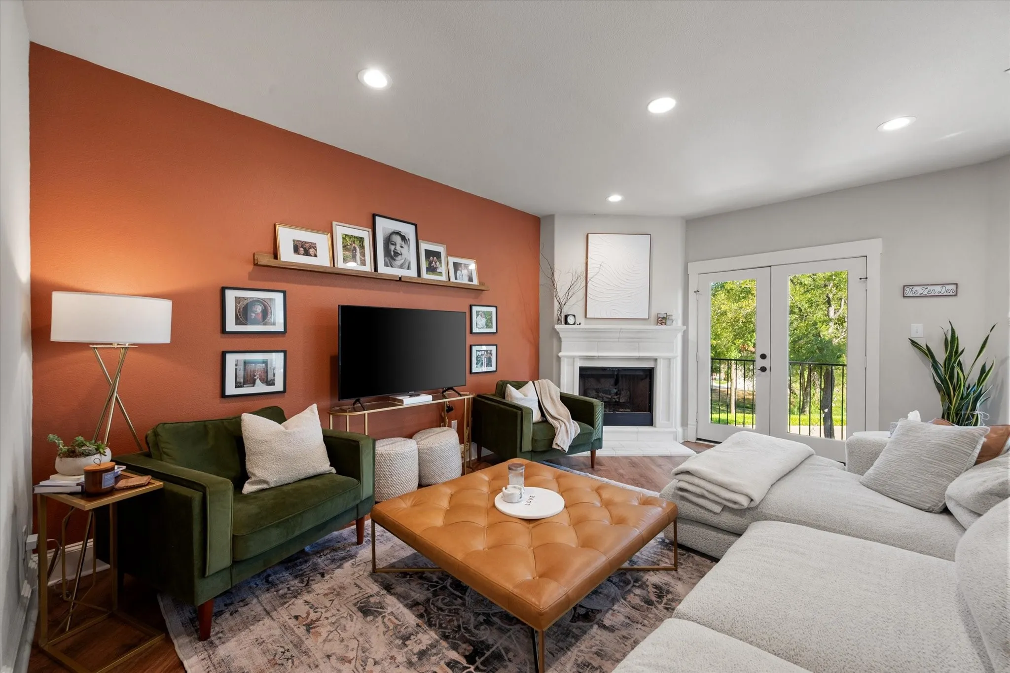 Open concept Living Area featuring LVP wood like flooring, a fireplace with white mantel, recessed lighting, and French doors leading out to the covered terrace overlooking the private backyard and greenbelt