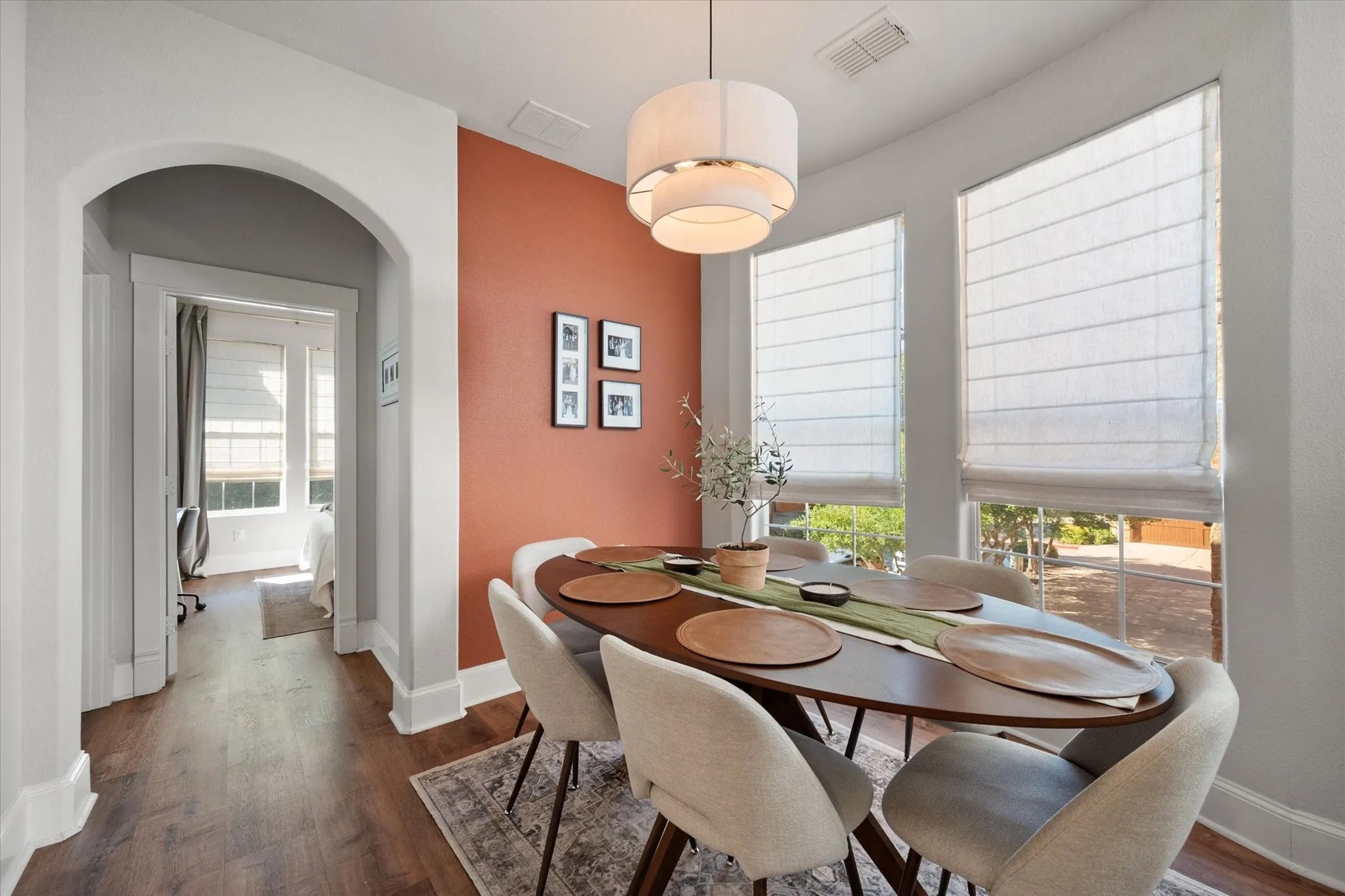 Dining Area featuring LVP wood like flooring, recessed lighting, modern light fixture, large windows with custom coverings, and an arched doorway leading to secondary bedrooms and bathrooms