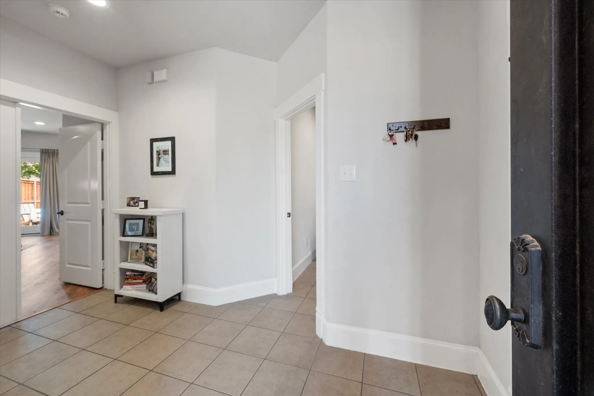Foyer on first floor featuring neutral paint, tile flooring, recessed lighting, white trim, and a paneled interior door leading to Primary Suite and Laundry Room