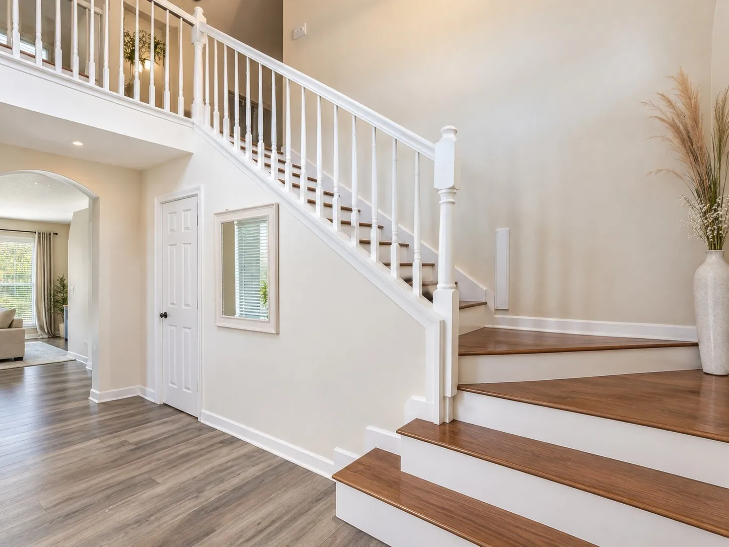 Hardwood staircase with white balusters, light-toned walls, and wood-finish flooring