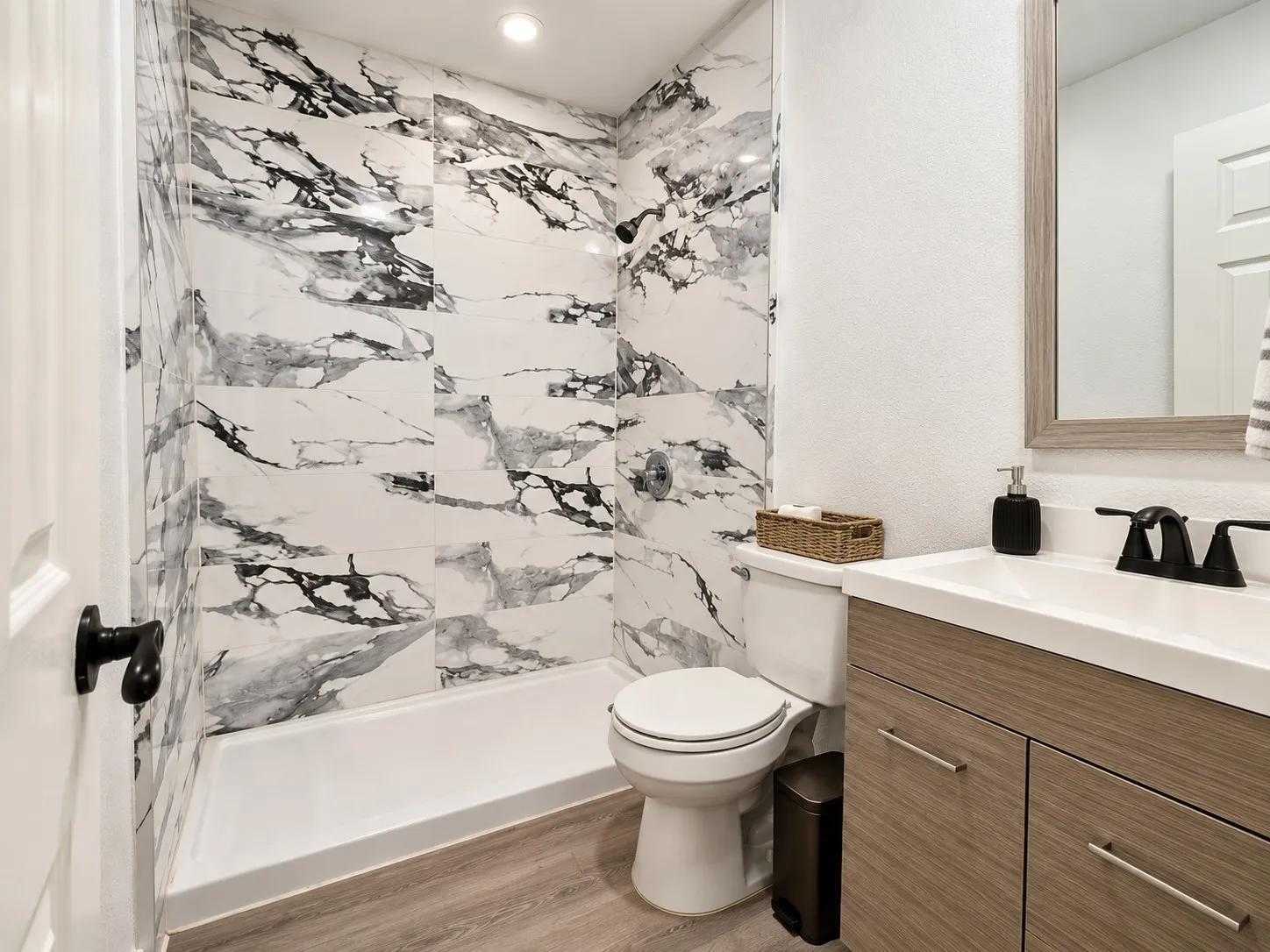 Shower with large-format tile surround, integrated shower base, and recessed lighting