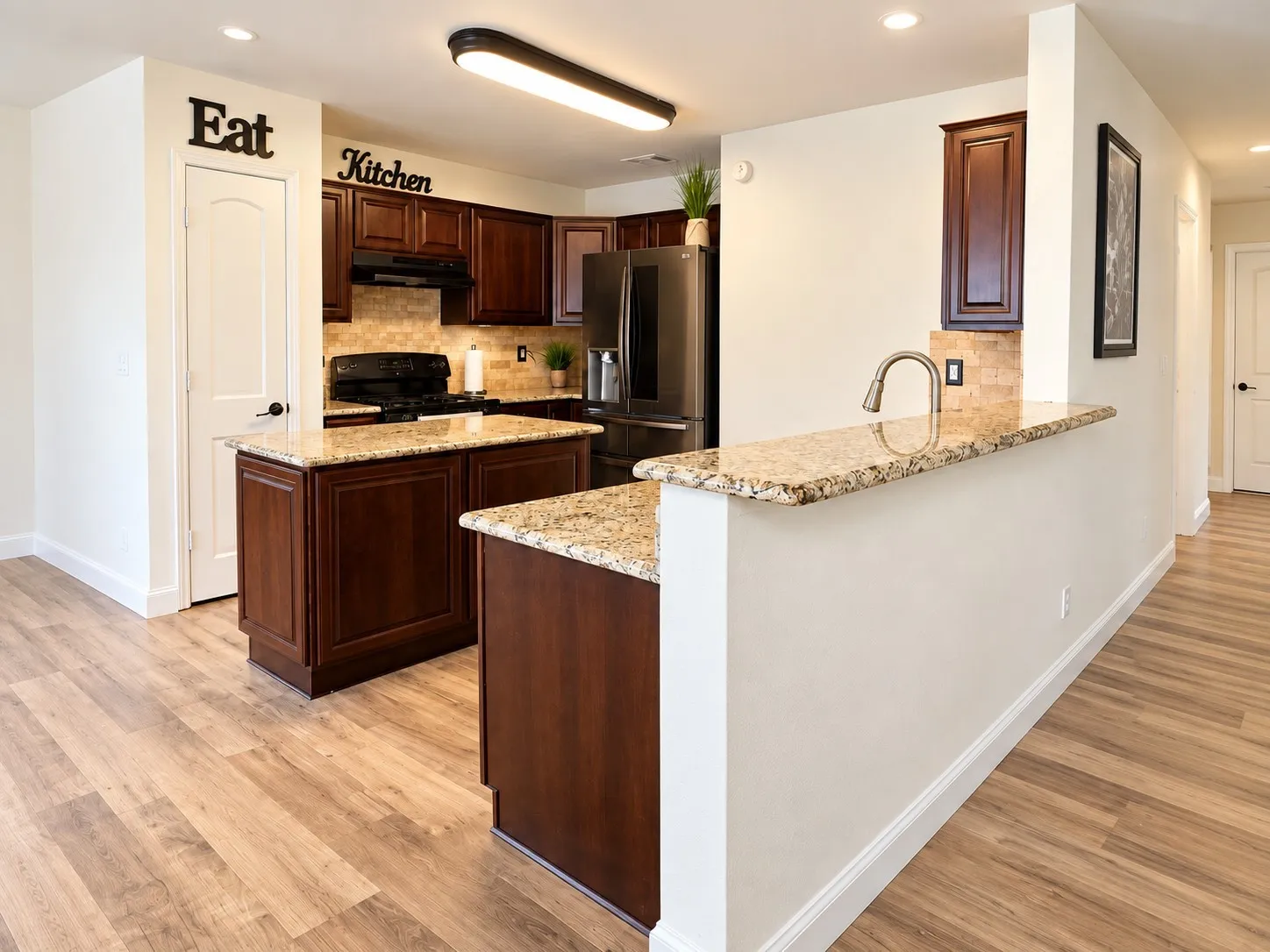 Kitchen featuring wood-finish flooring, dark wood cabinetry, light-toned stone countertops, and a stone-tiled backsplash