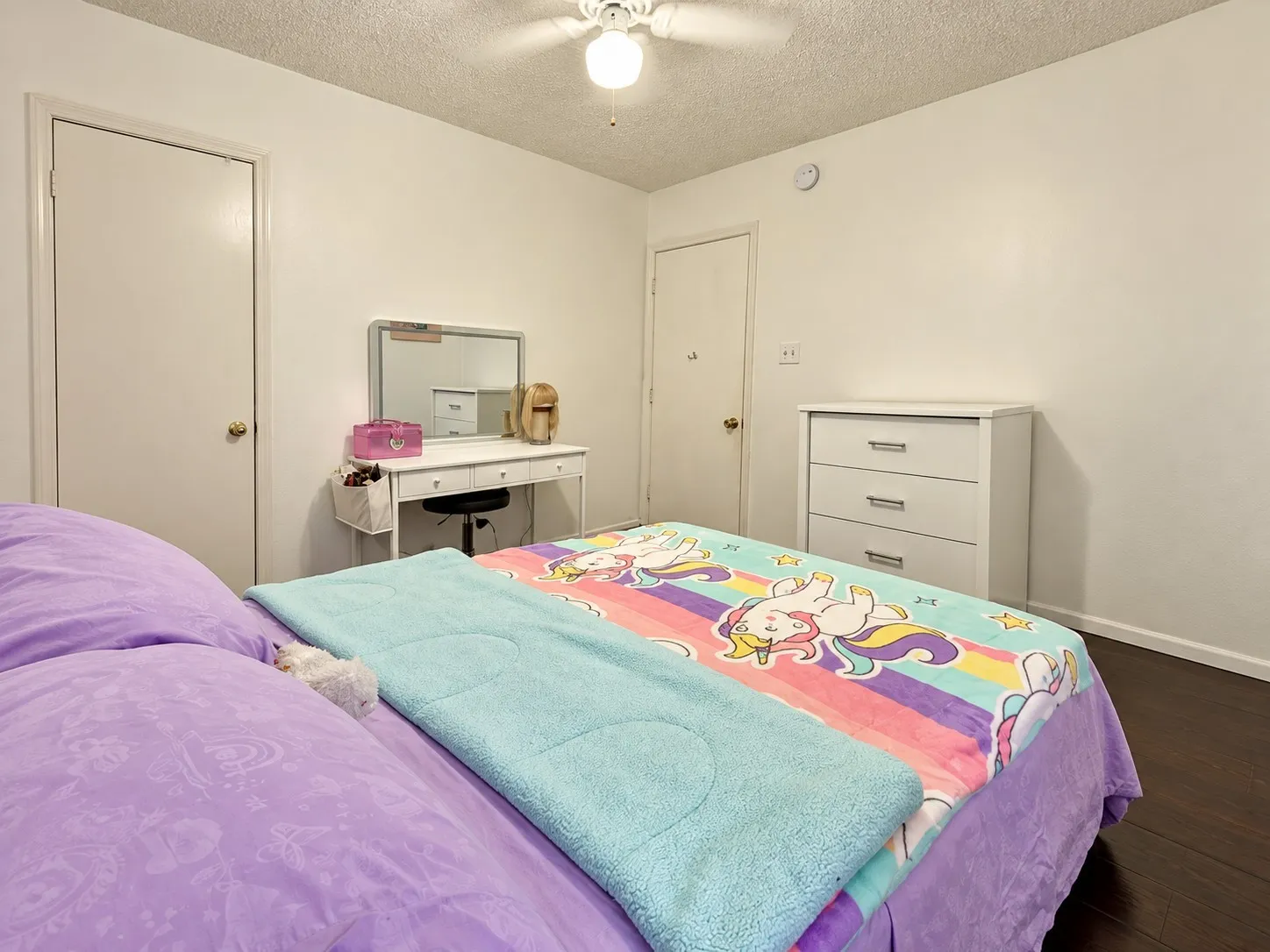Wood-finish flooring with white baseboards, white walls, and a ceiling fan with light fixture