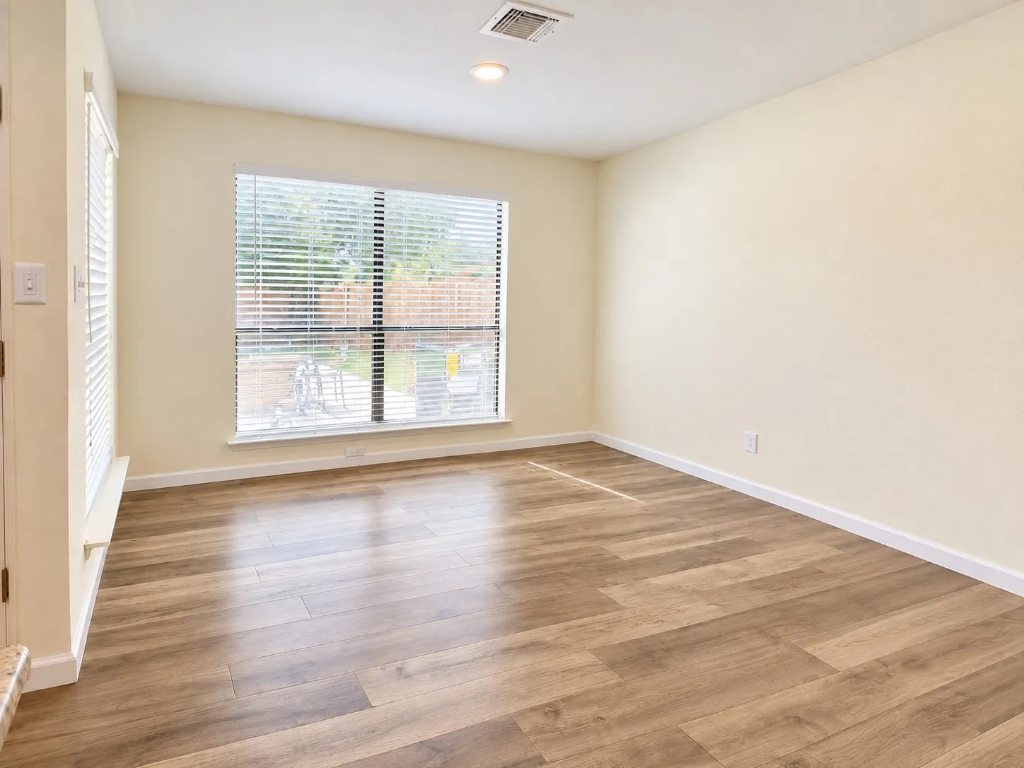 Wood-finish flooring, recessed lighting, and a large window with blinds