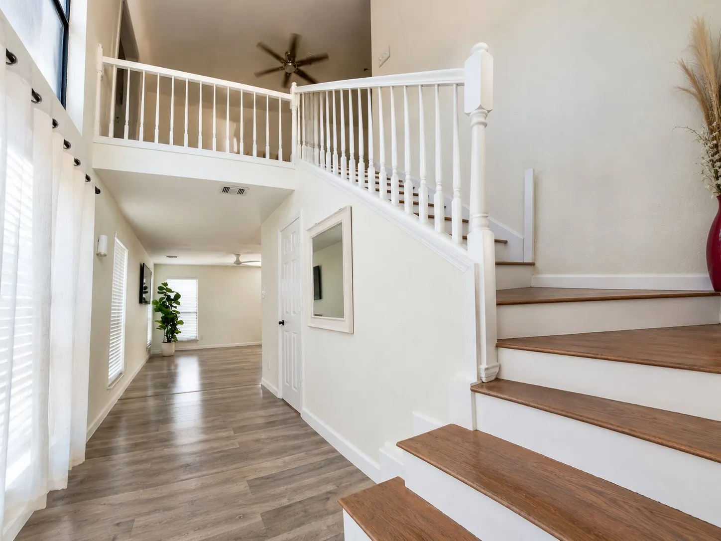 Two-story entry featuring wood-finish flooring, a white spindle staircase, and an upper-level balcony