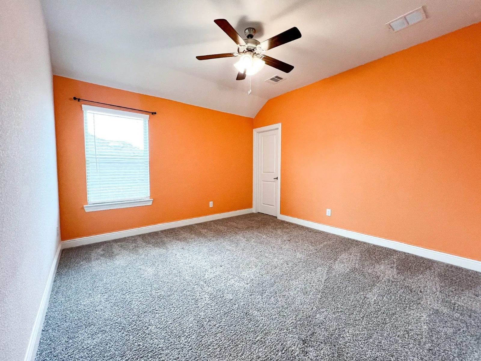 Recessed window with blinds, ceiling fan with light fixture, neutral carpet flooring, and a solid interior door