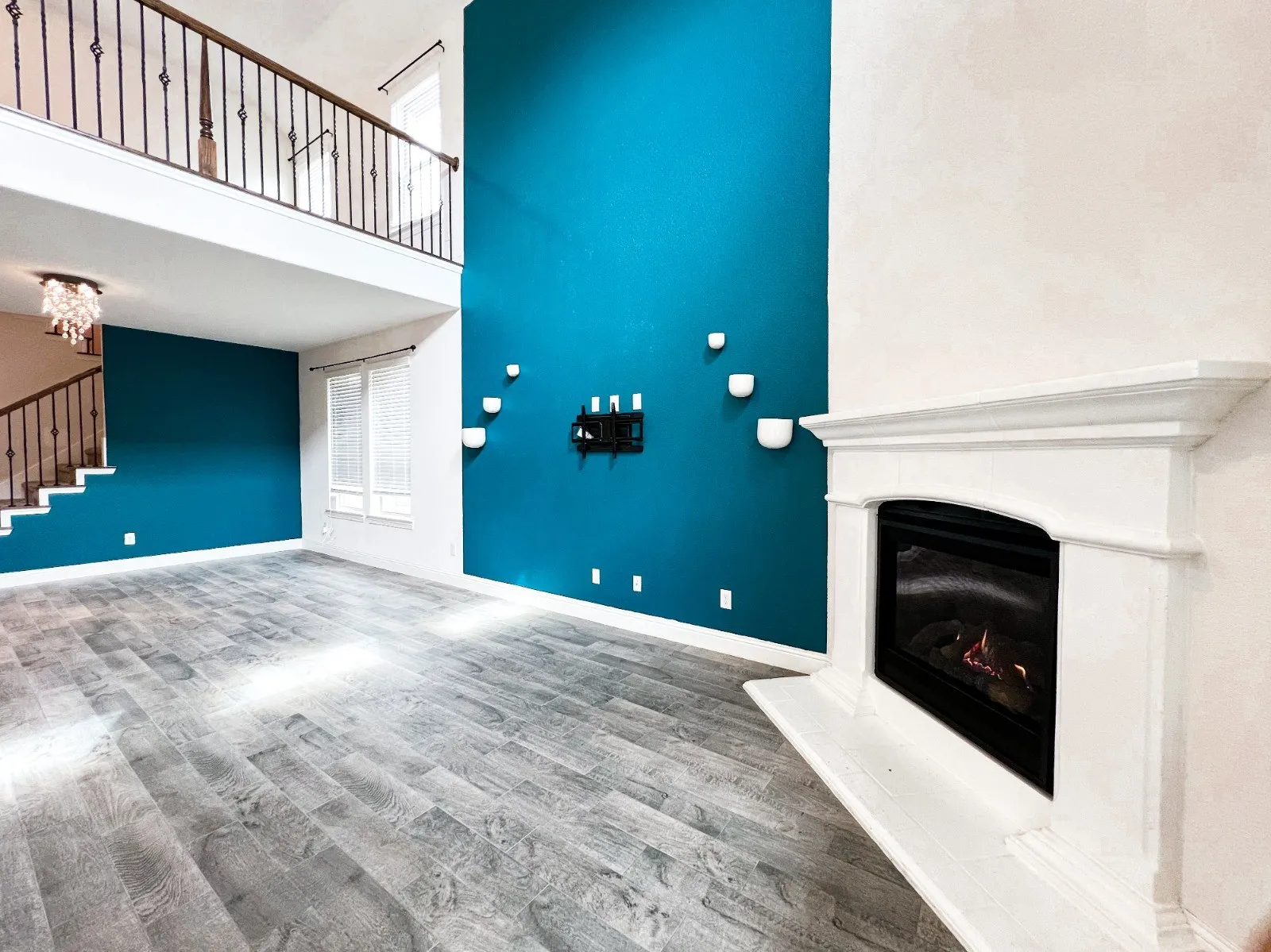 Two-story interior with wood-finish flooring, a decorative fireplace, and an open balcony featuring wrought iron railing