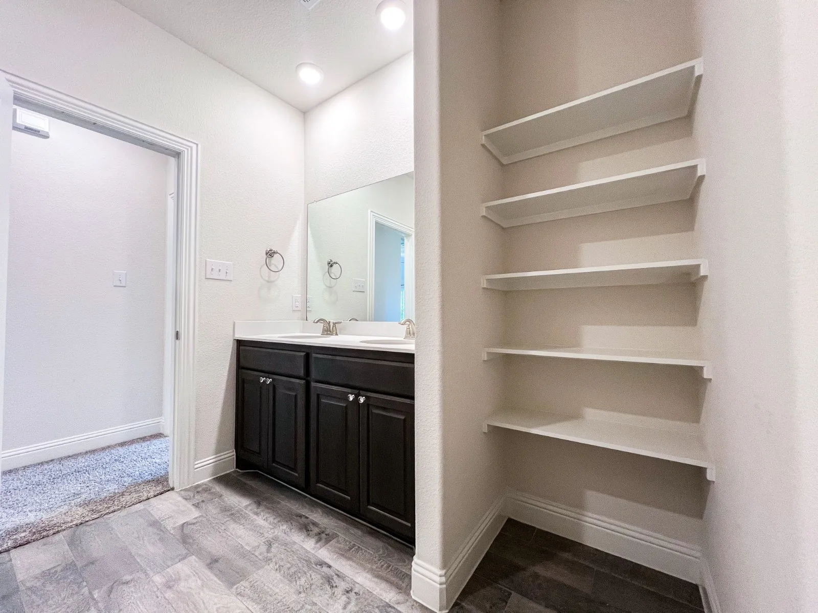 Vanity with dual sinks, dark wood-finish cabinetry, and white countertops