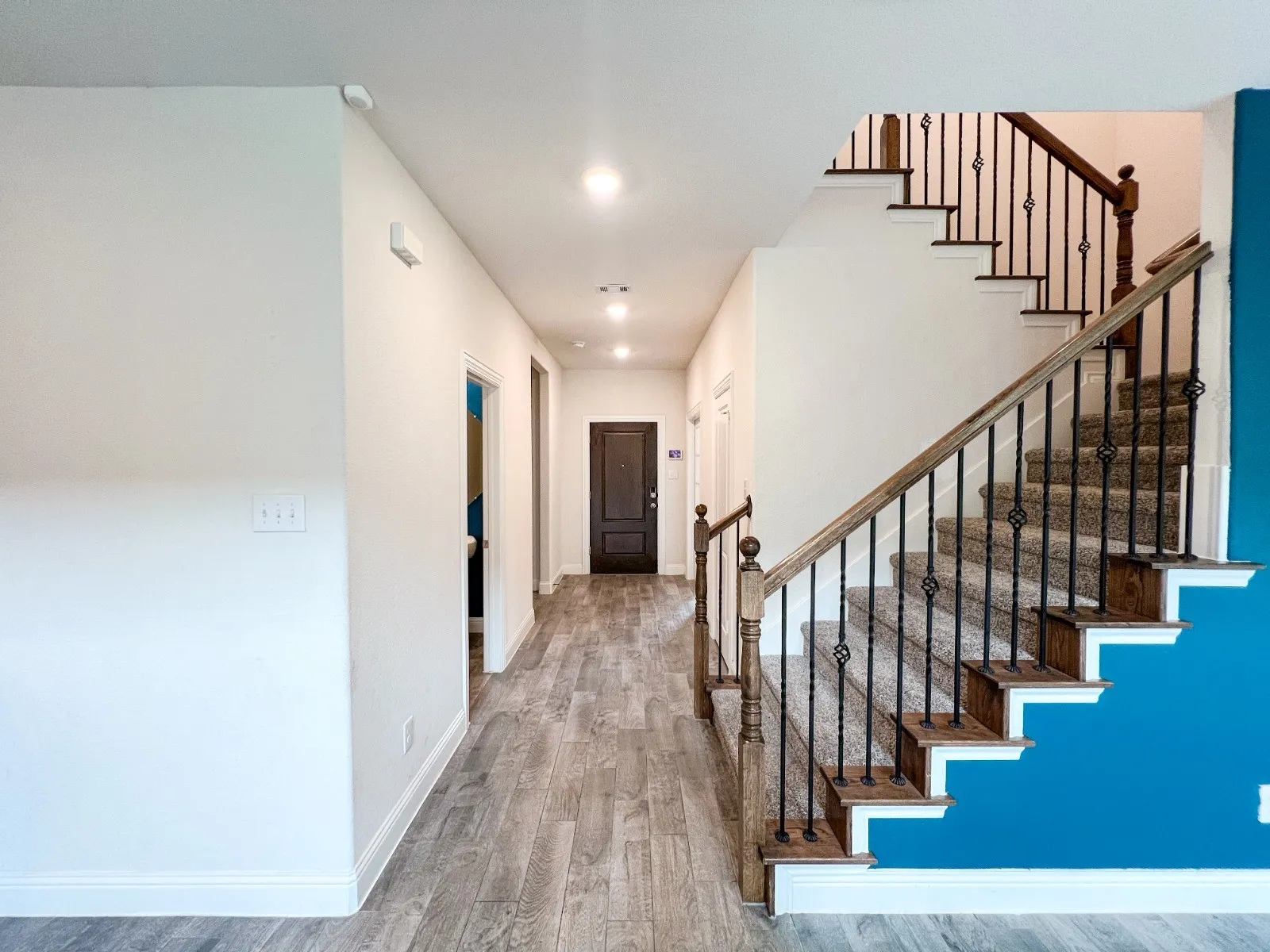 Wood-finish flooring, recessed lighting, and a dark paneled entry door