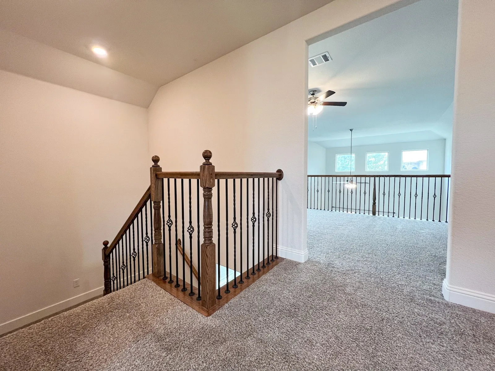 Open loft area featuring plush carpeting and a decorative wrought iron railing