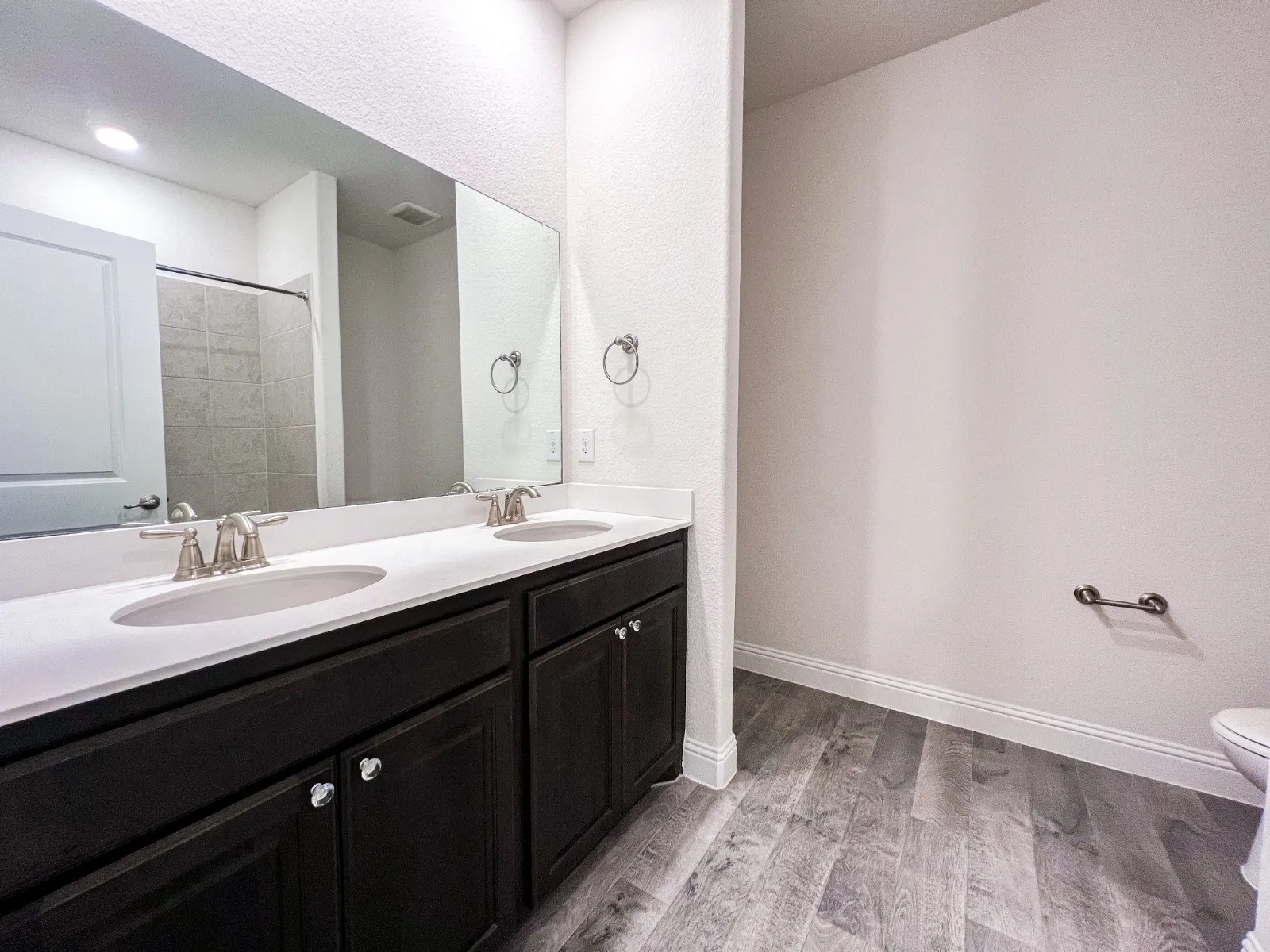 Double vanity with white countertops, dark wood-finish cabinetry, and brushed nickel fixtures